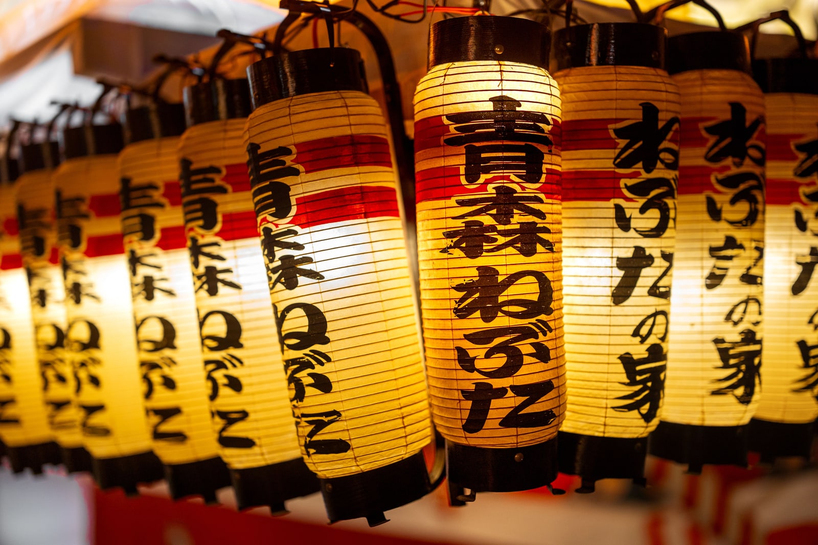 A row of lit paper lanterns printed with "Aomori Nebuta" in black brush lettering