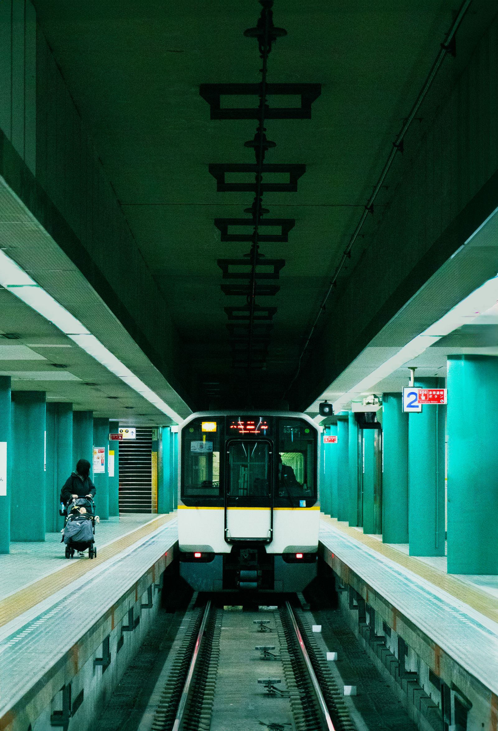 An underground railway platform in Japan at night; a train waits at platform 2.