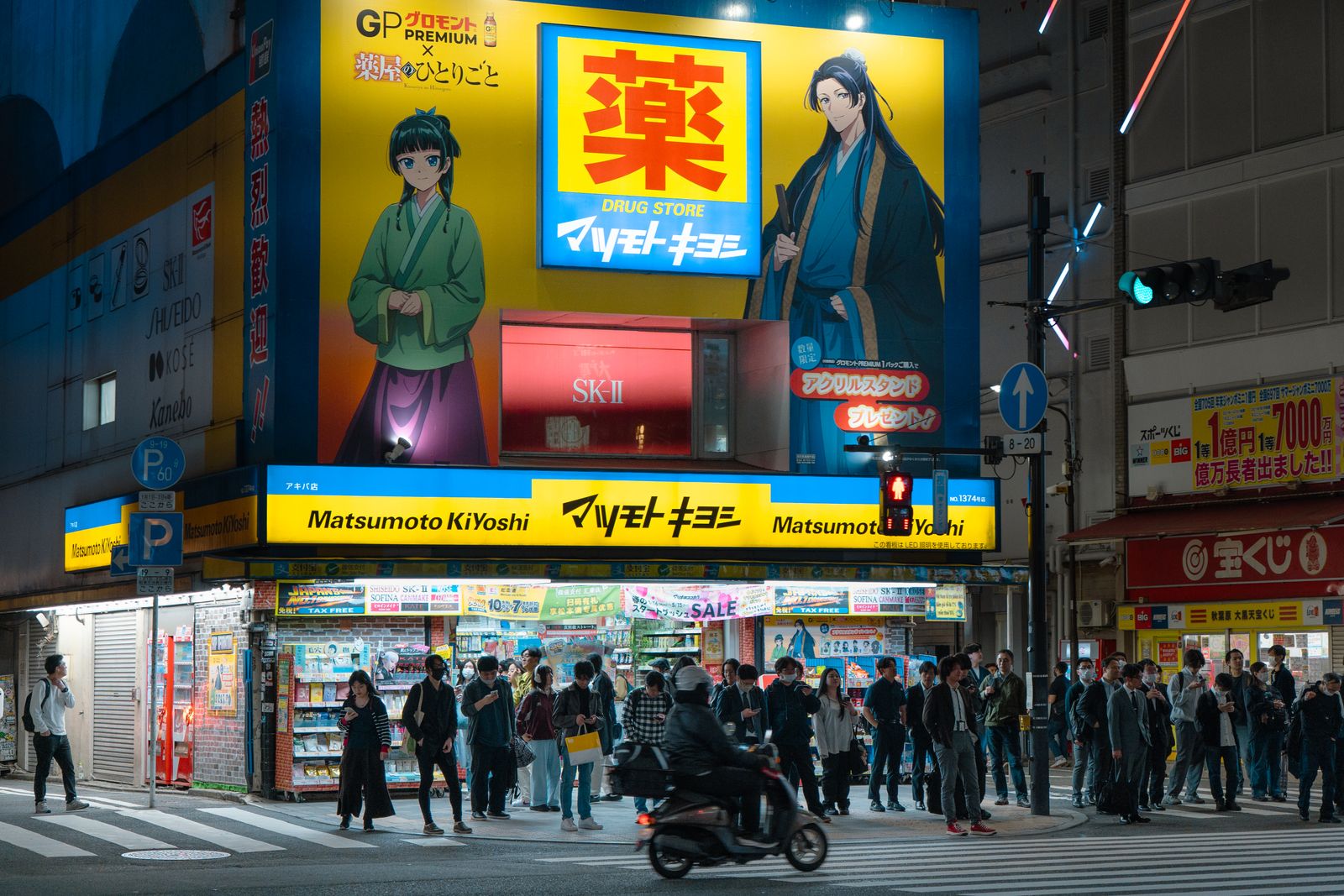 A Matsumoto Kiyoshi branch lit up at a Tokyo crossing at night, with a large yakuji drugstore sign and tax-free banners.
