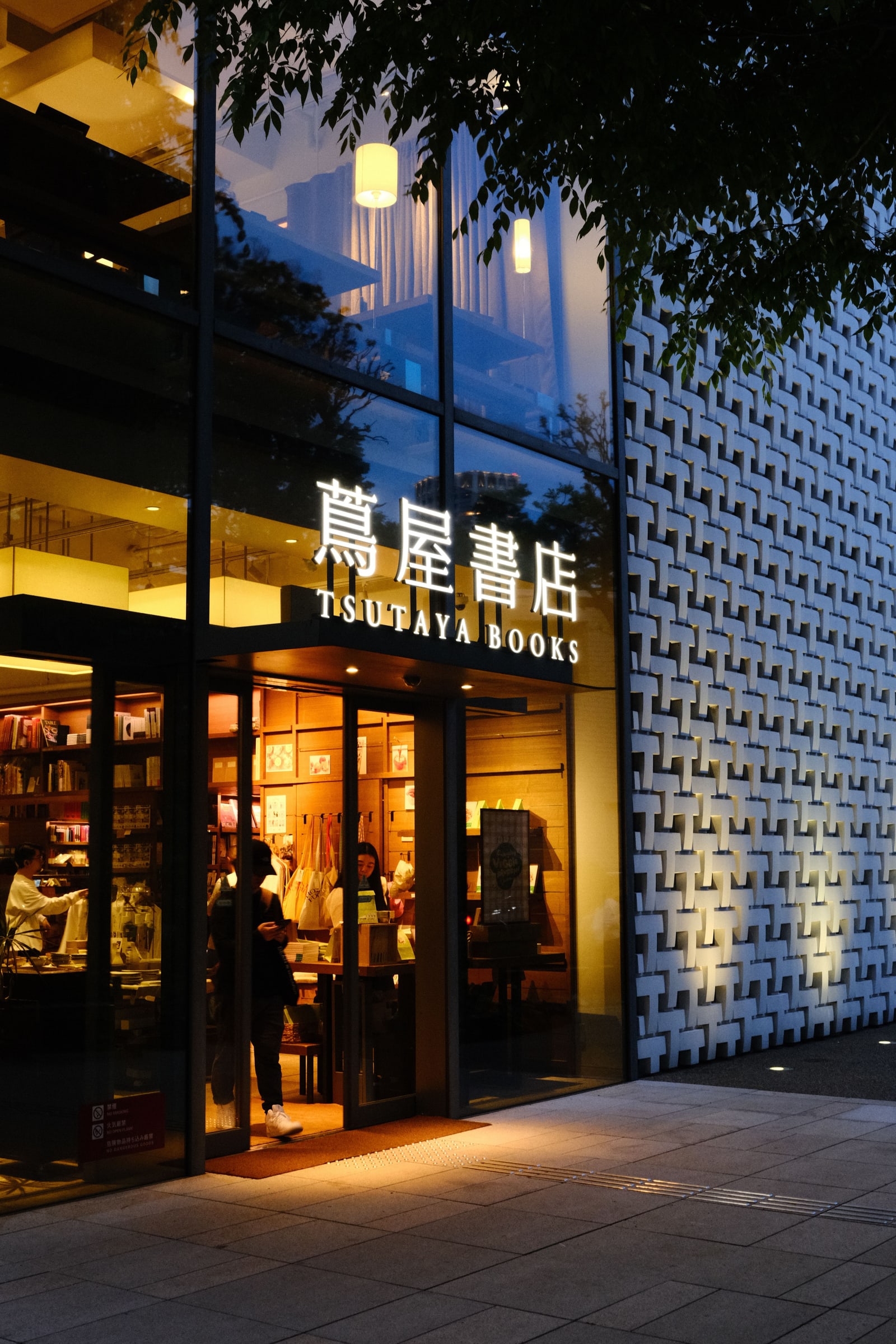 Daikanyama T-Site's Tsutaya Books entrance in the early evening, its sign lit above glass doors