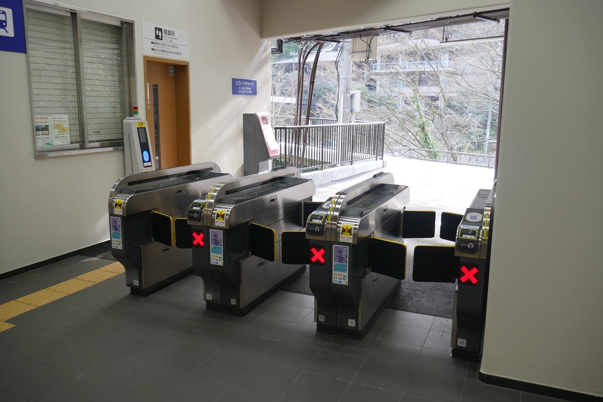 Automatic ticket gates at a Japanese station. An IC card reader panel and signs for IC card recharging and fare adjustment are visible.