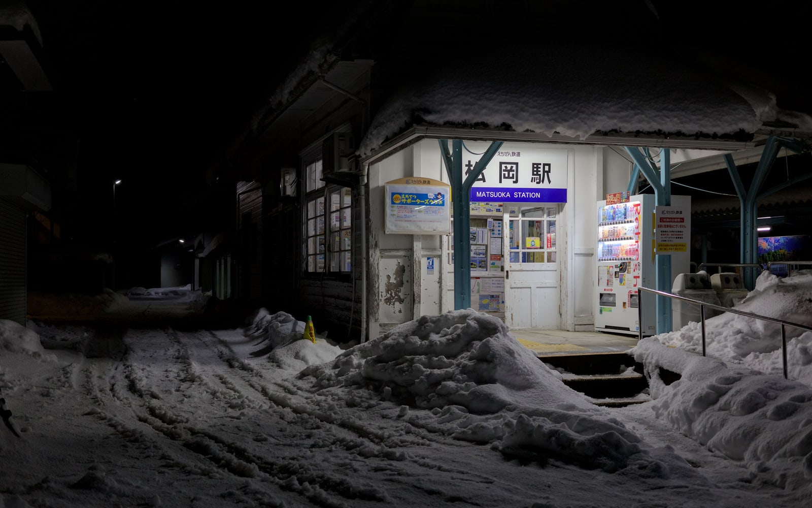 Matsuoka Station on the Echizen Railway at night, snow piled high in front of its lit entrance