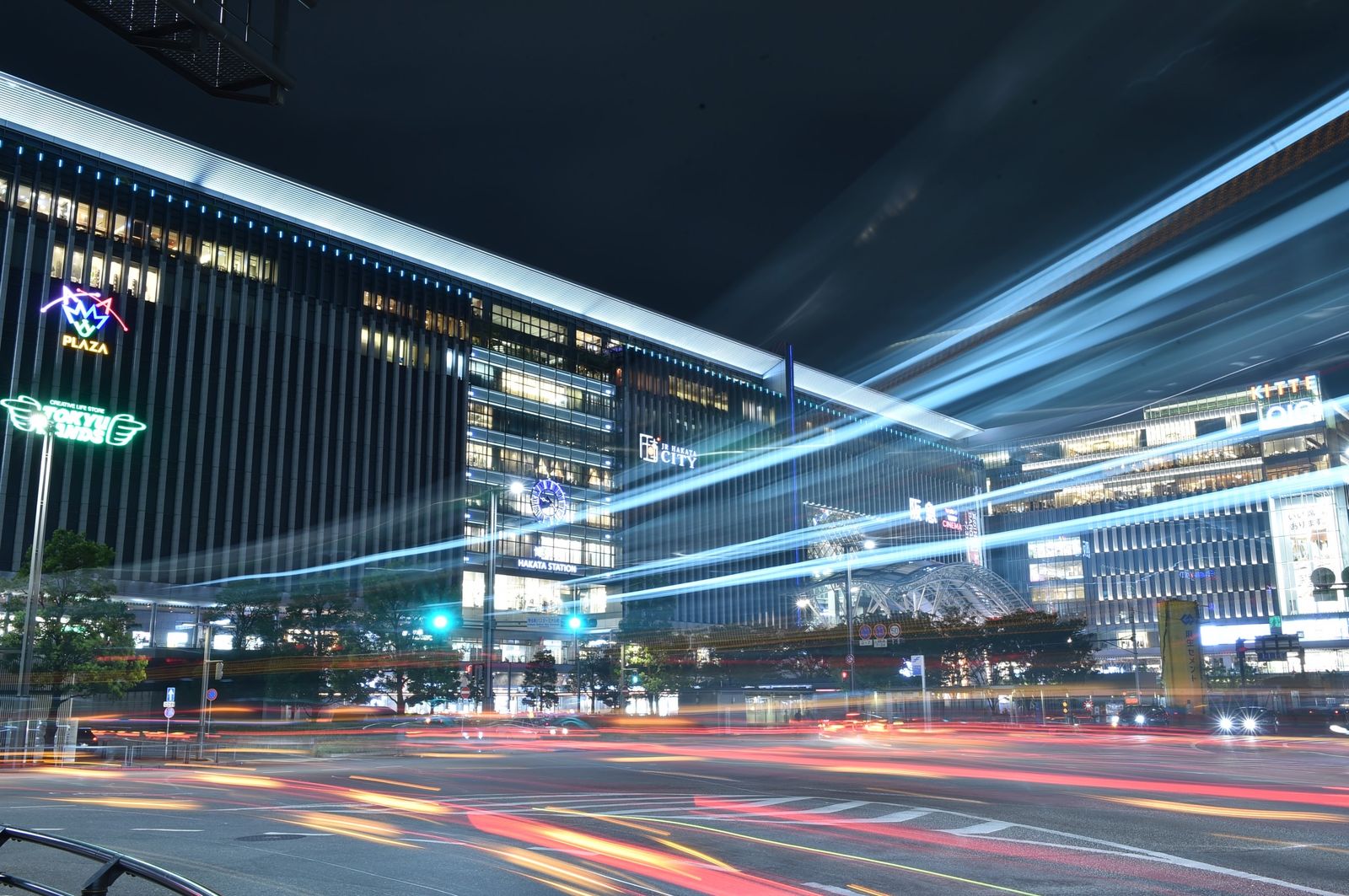 Hakata Station at night, the JR Hakata City building lit above the plaza with the station signage legible across the frontage.