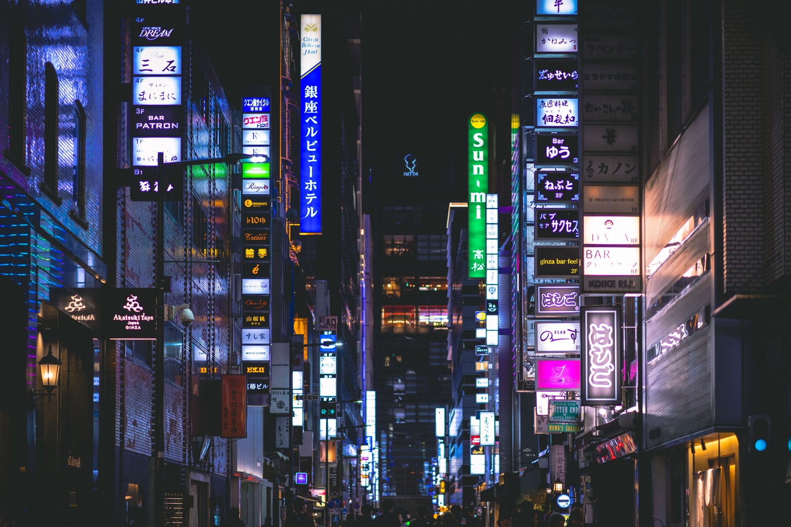 A narrow Ginza side street at night with stacked illuminated vertical signs for bars and small restaurants on both sides