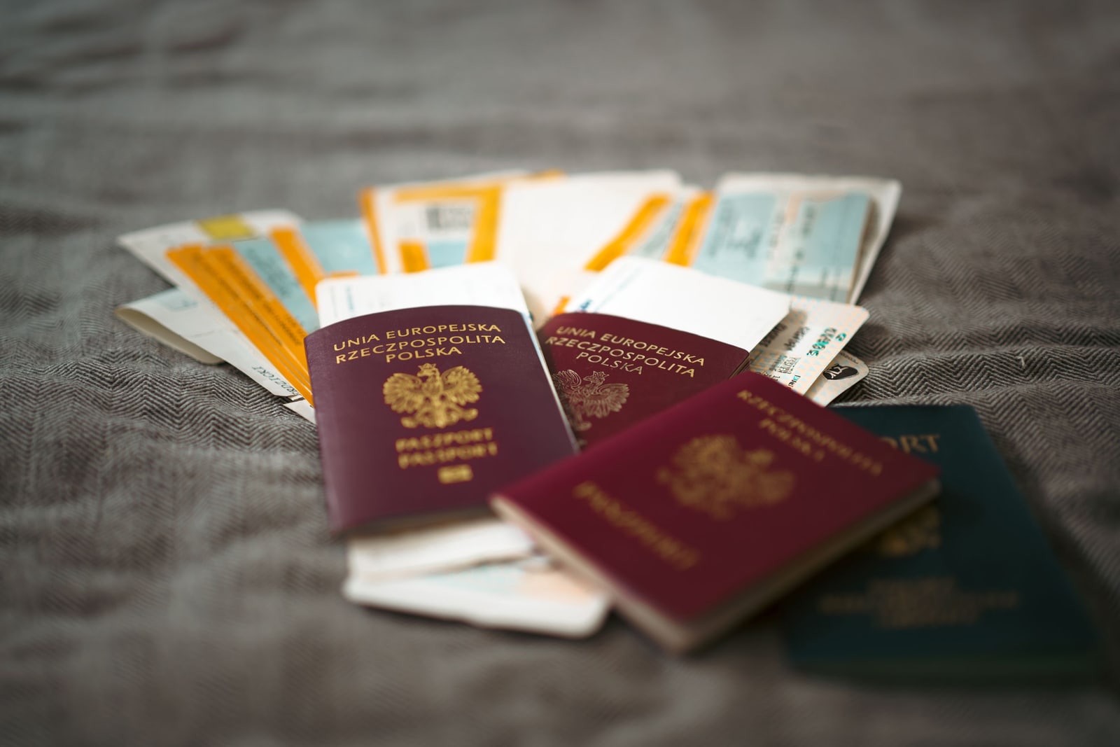 Two red passports lying on a pile of paper travel documents on a gray cloth.