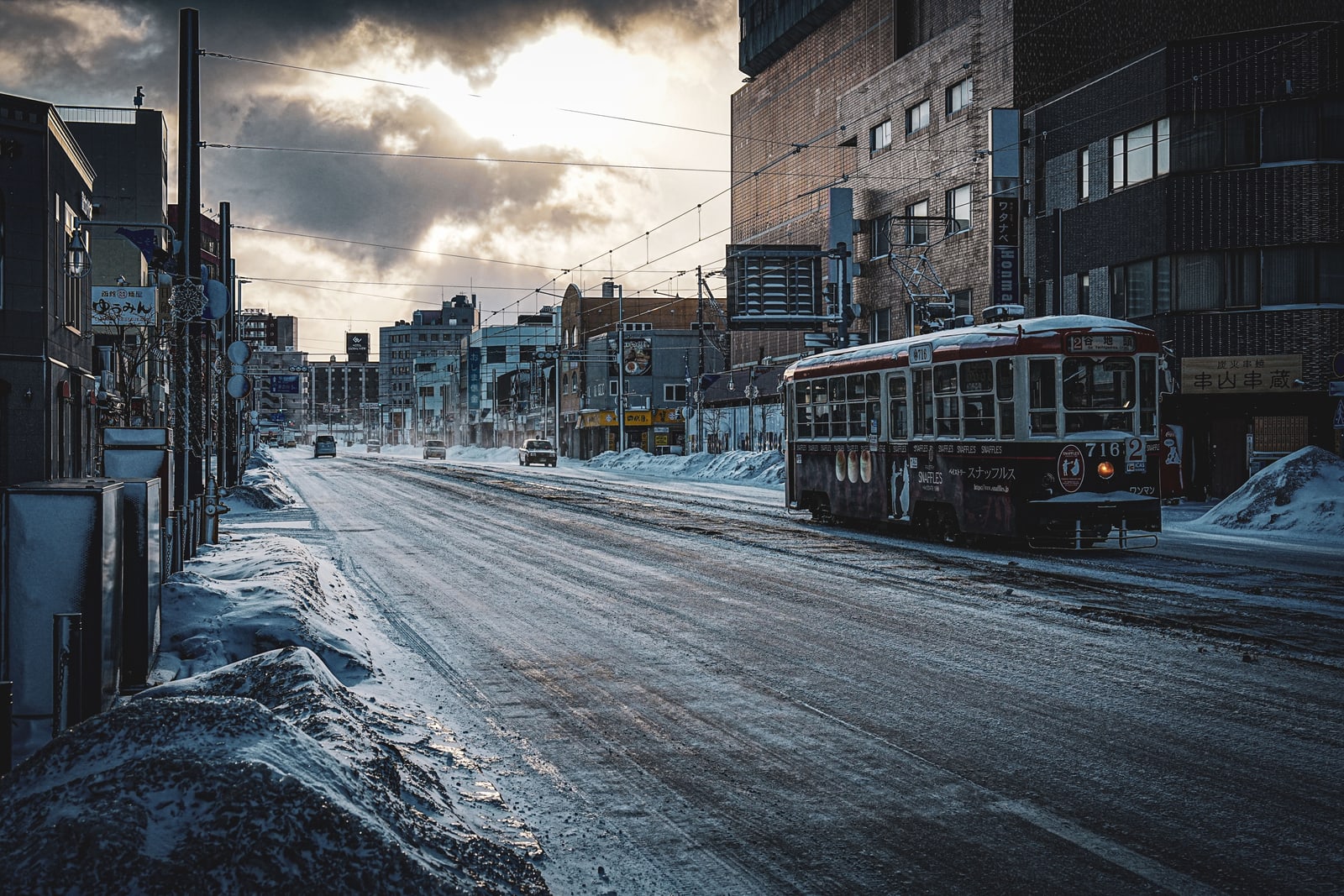 A dark-red tram on a snow-packed city street under heavy cloud