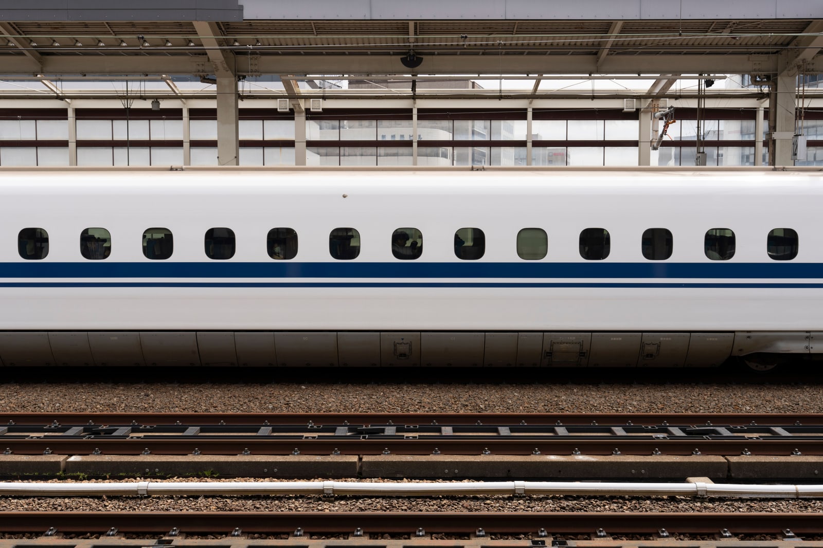 The long white side of a Shinkansen bullet train standing at a station platform.