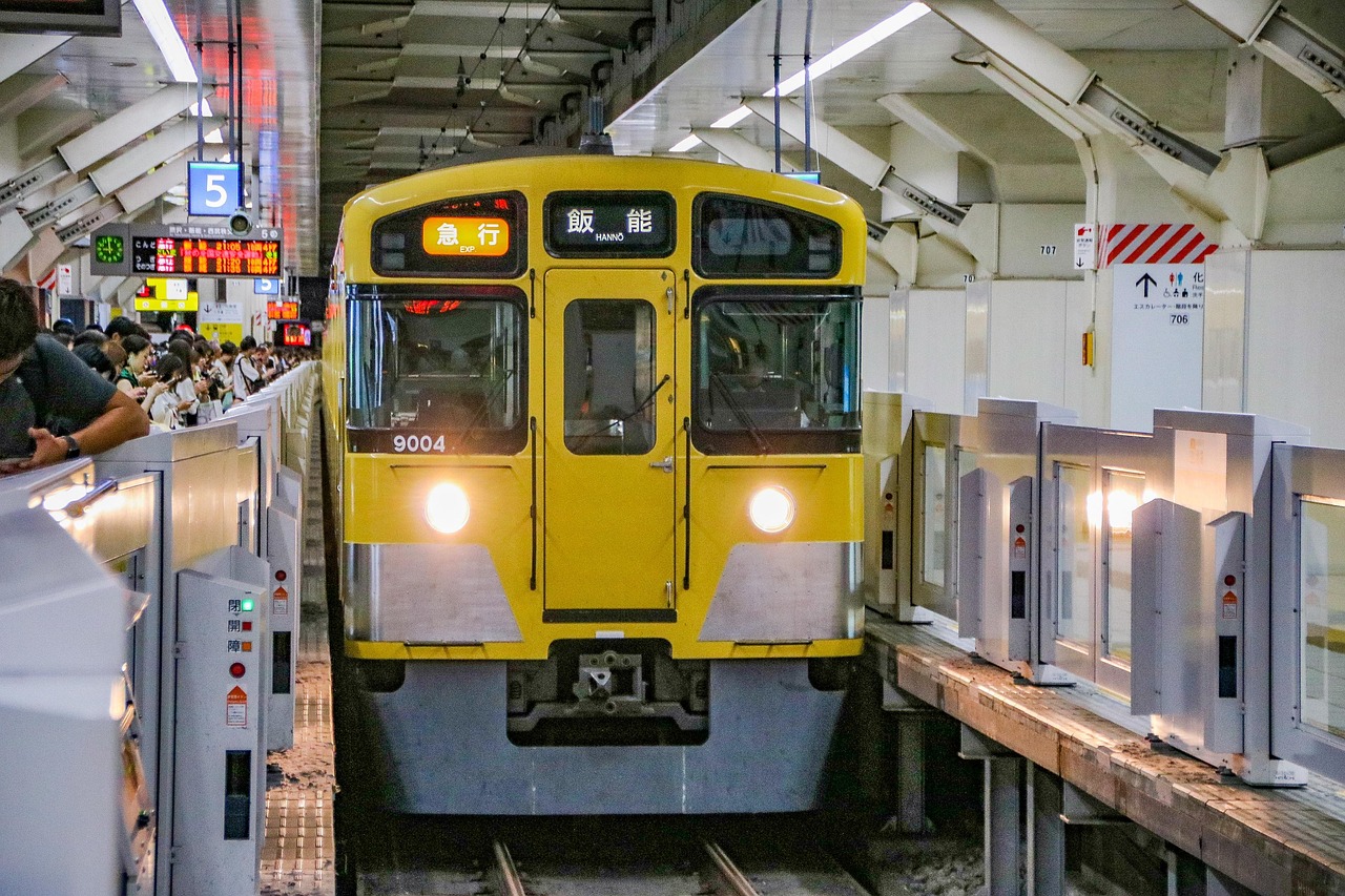 A yellow Seibu commuter train at a terminal platform, ticket gates beside it.