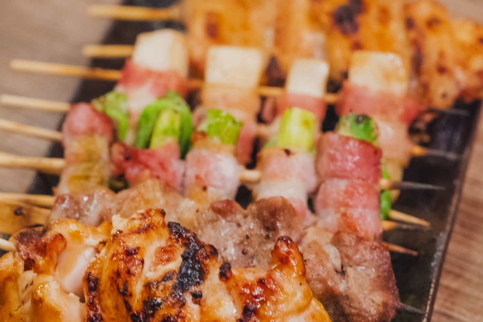 Grilled yakitori skewers lined up on a long plate.