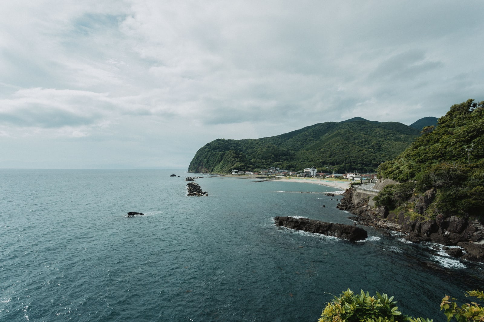 A small seaside town and beach below forested hills on the west coast of the Izu Peninsula, as the photographer places it