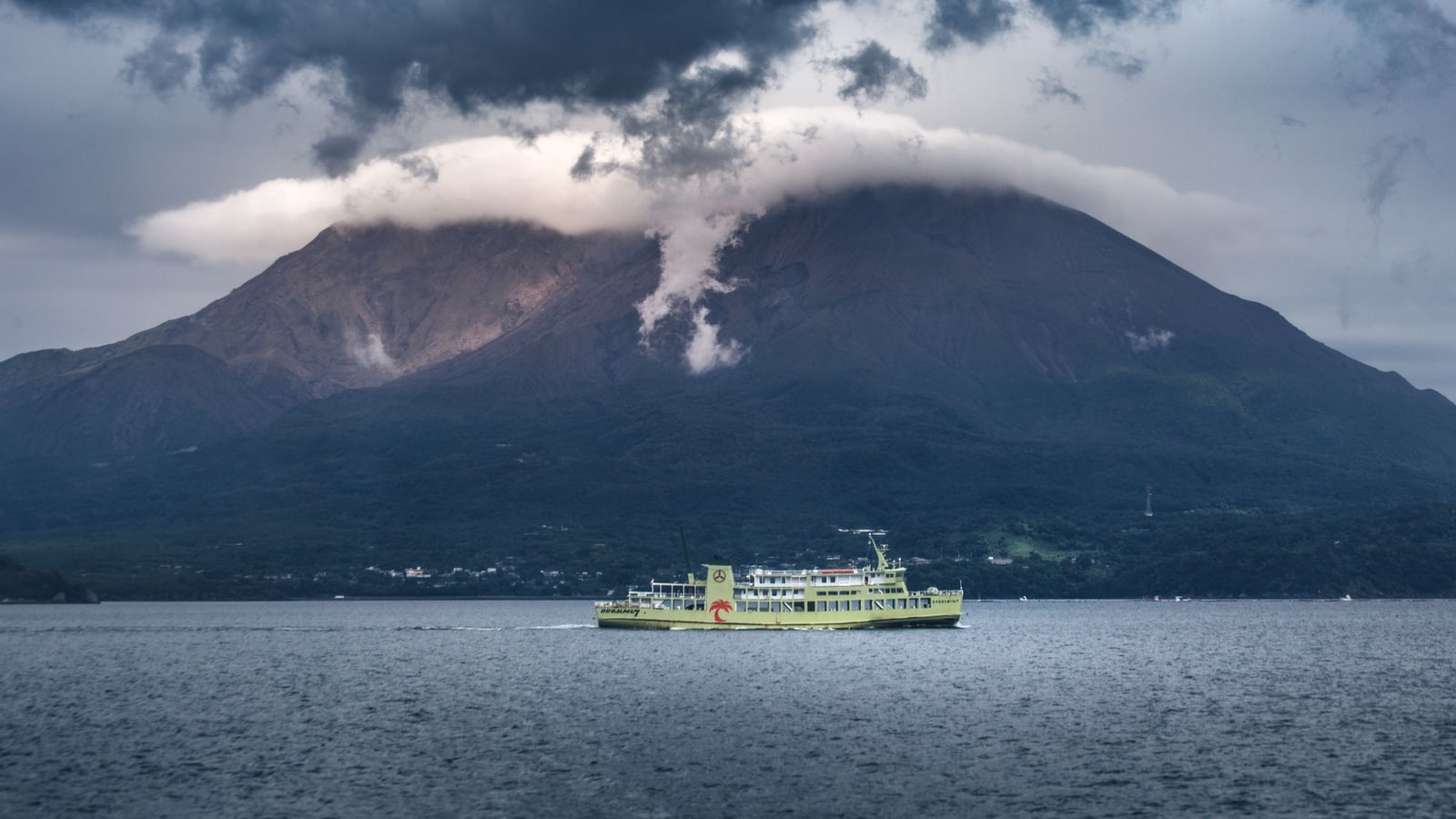A ferry crossing Kagoshima Bay in front of Sakurajima, cloud over the summit