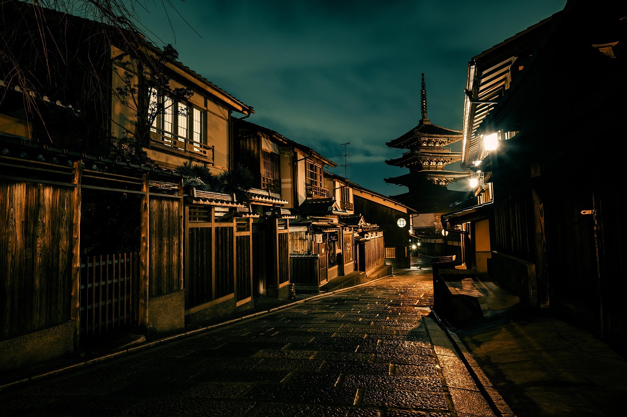 An empty stone-paved lane in old Kyoto at dusk, wooden townhouses on both sides and a five-story pagoda at the end.