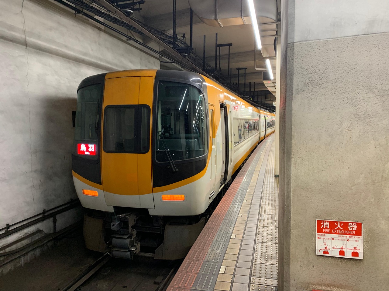 An orange and white Kintetsu limited express at an underground platform, its destination board reading Toba.