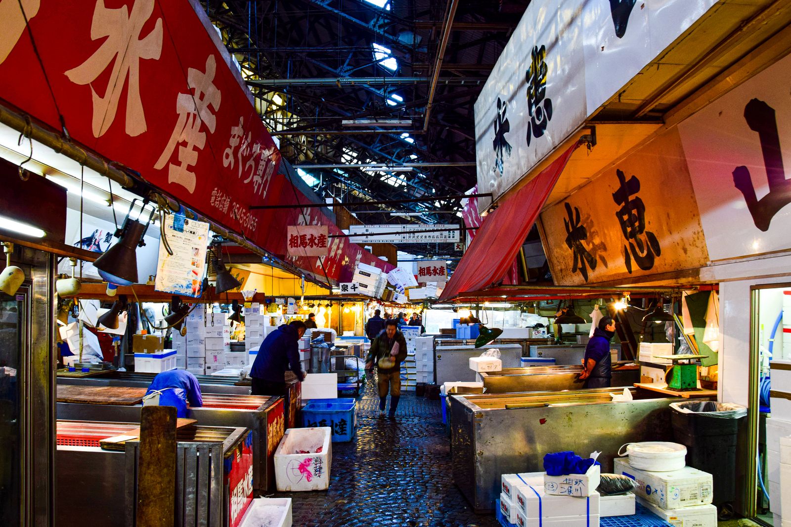 A Tokyo fish market aisle, stall awnings printed with suisan and maguro-senmon.