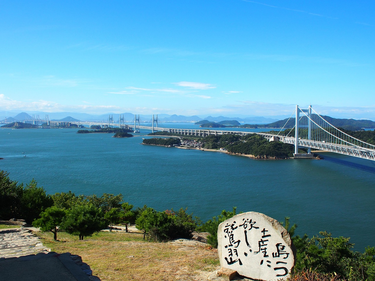 The Seto Ohashi bridges and islands of the Seto Inland Sea seen from Mt. Washuzan, a carved stone in the foreground