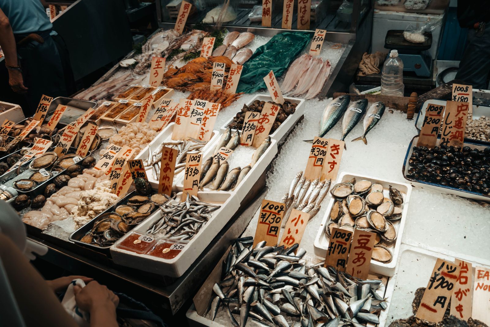 Whole fish laid on ice at a Kyoto stall, with handwritten Japanese tags, one reading はも.