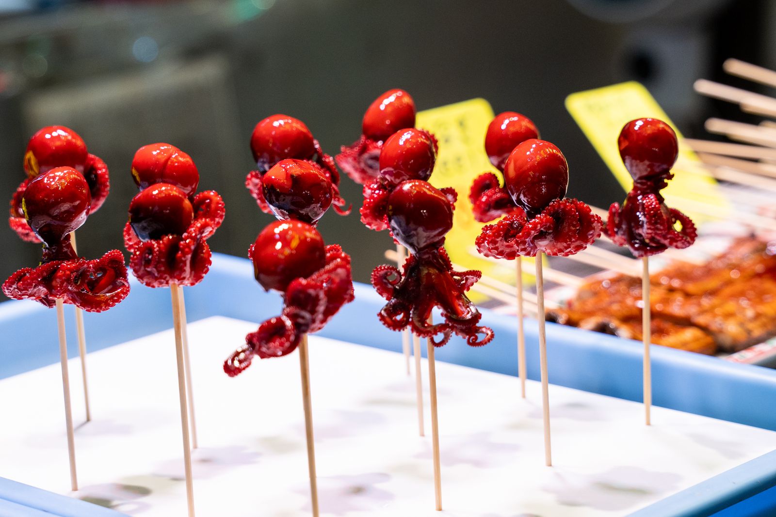 Glazed baby-octopus skewers standing upright in a tray at a Kyoto street market.