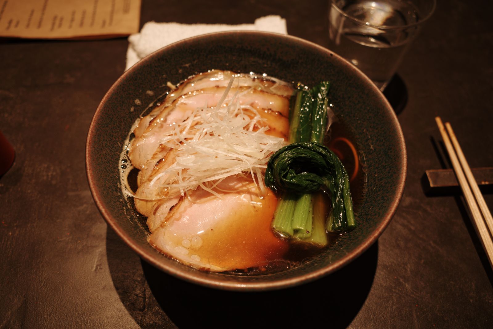 A clear-broth ramen with chashu, green onion and greens in a Kyoto restaurant.