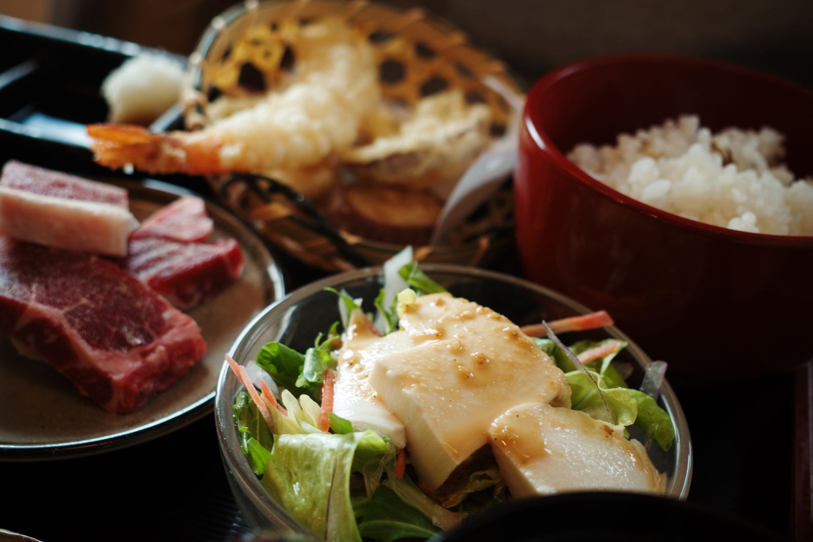 A set meal in a Kyoto restaurant: rice, tofu salad, prawn tempura and sliced raw beef for the table grill.
