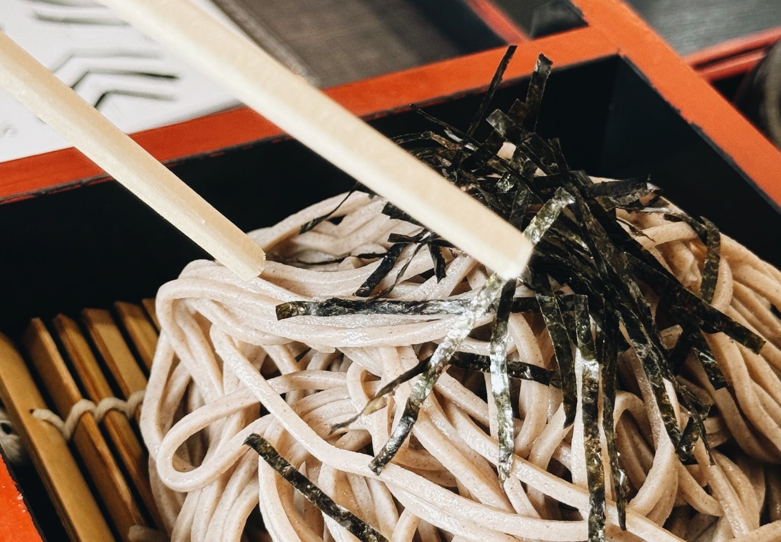 Cold zaru soba topped with nori in a lacquer box, chopsticks alongside, in Kyoto.