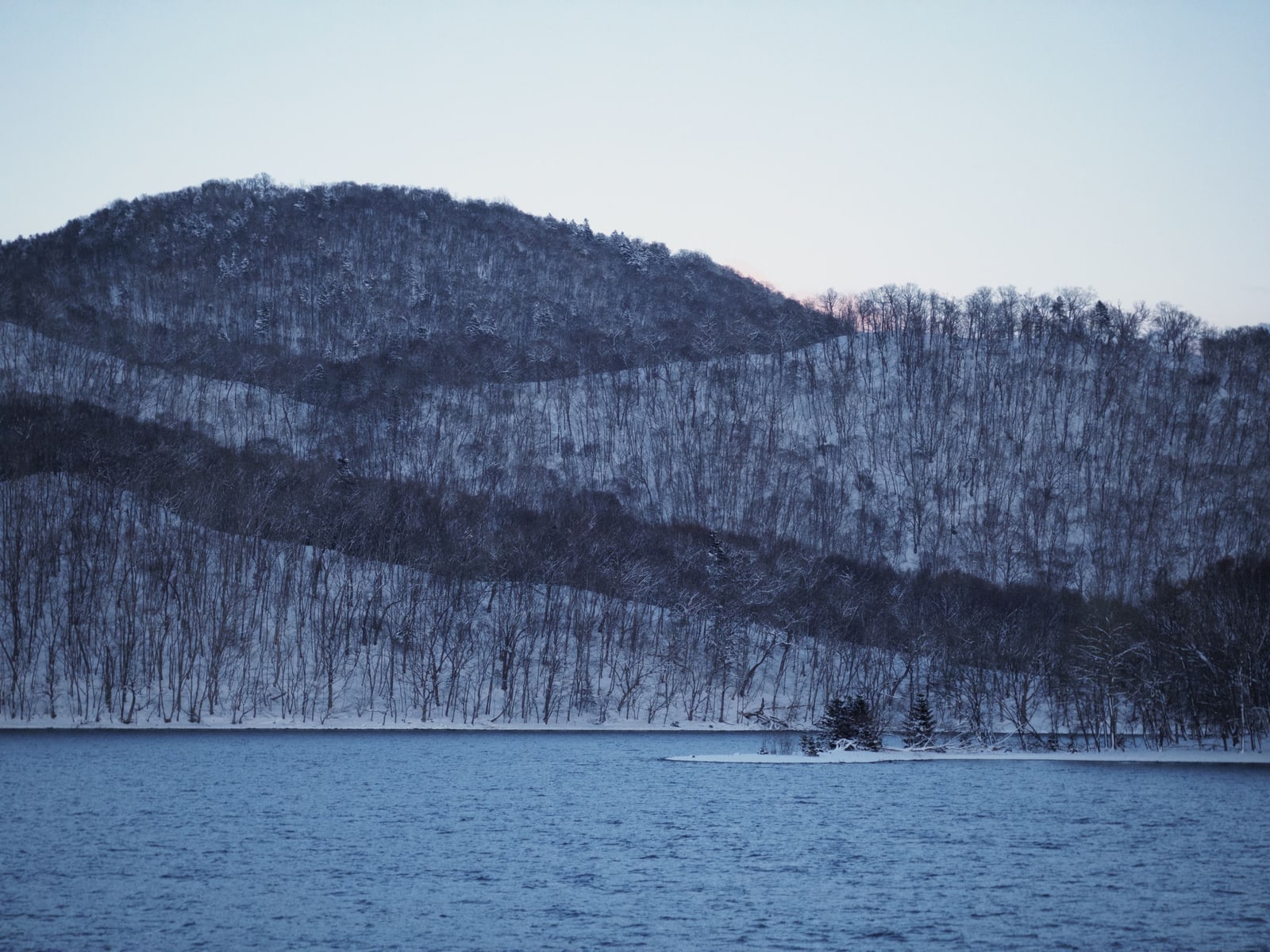 Snow-covered wooded hills above Lake Toya at winter dusk, Hokkaido