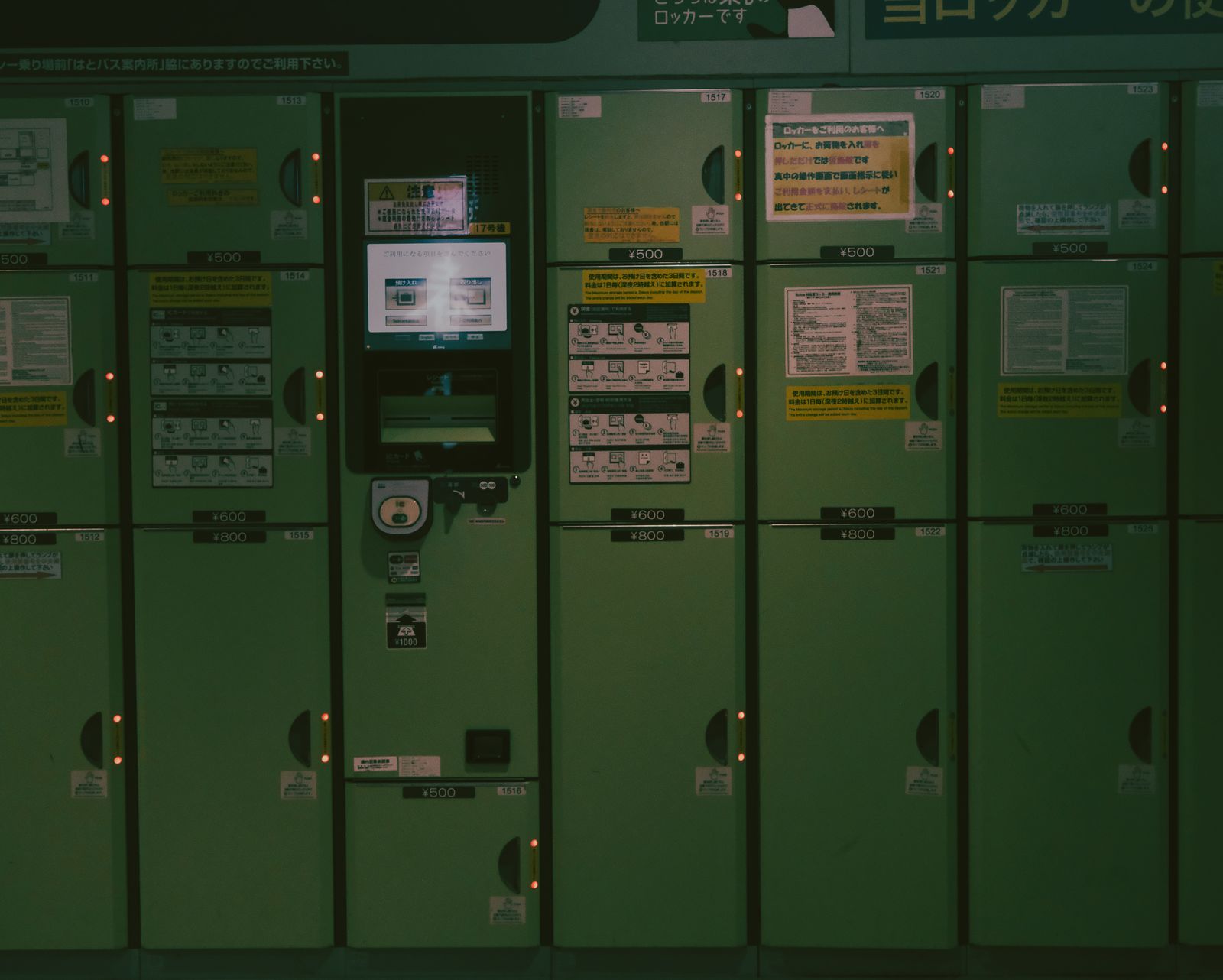A bank of coin lockers in a Japanese station, with a payment and instruction panel set into the center of the row.