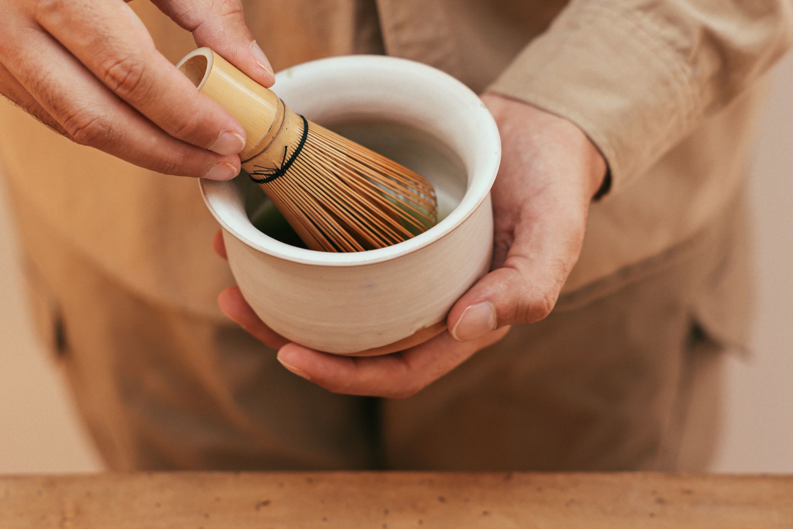 A bamboo tea whisk held in one hand, its tines fanned out.
