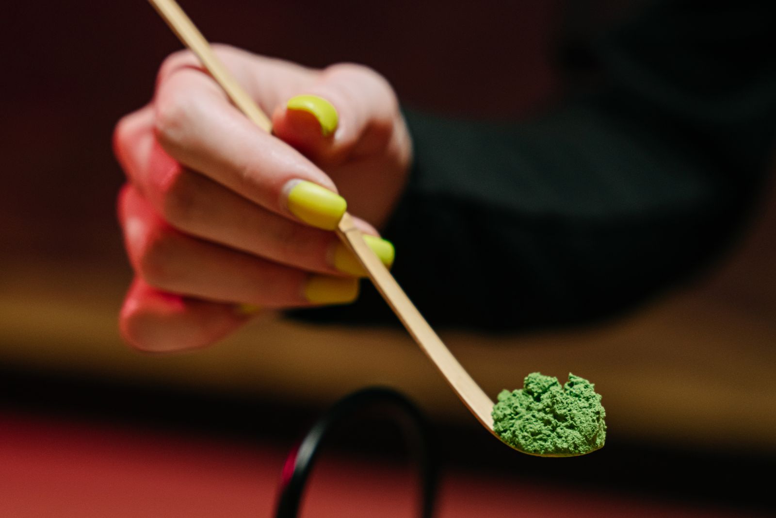 A spoonful of matcha powder photographed close enough to read its texture.