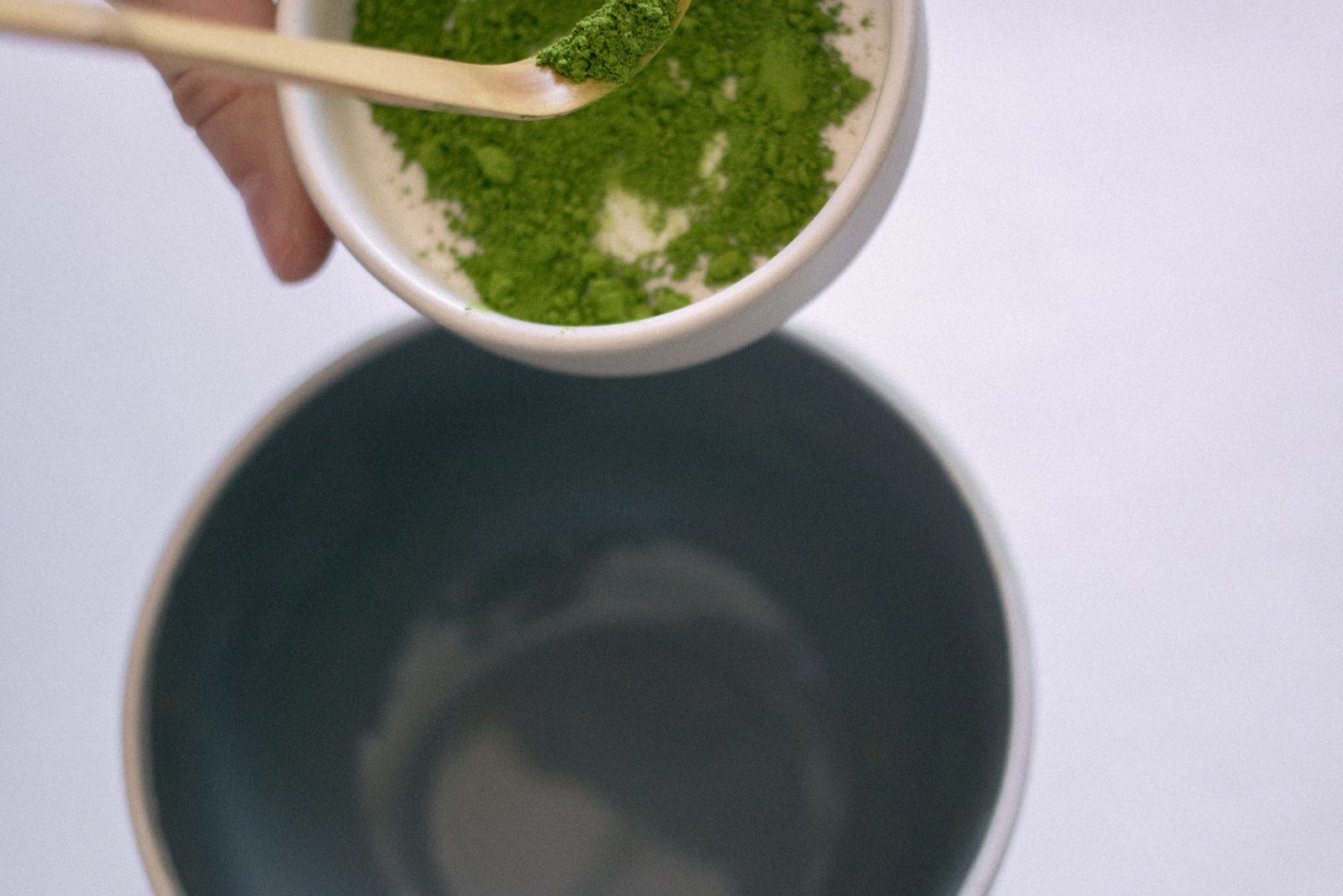 Matcha powder being pushed through a small sieve into a cup.