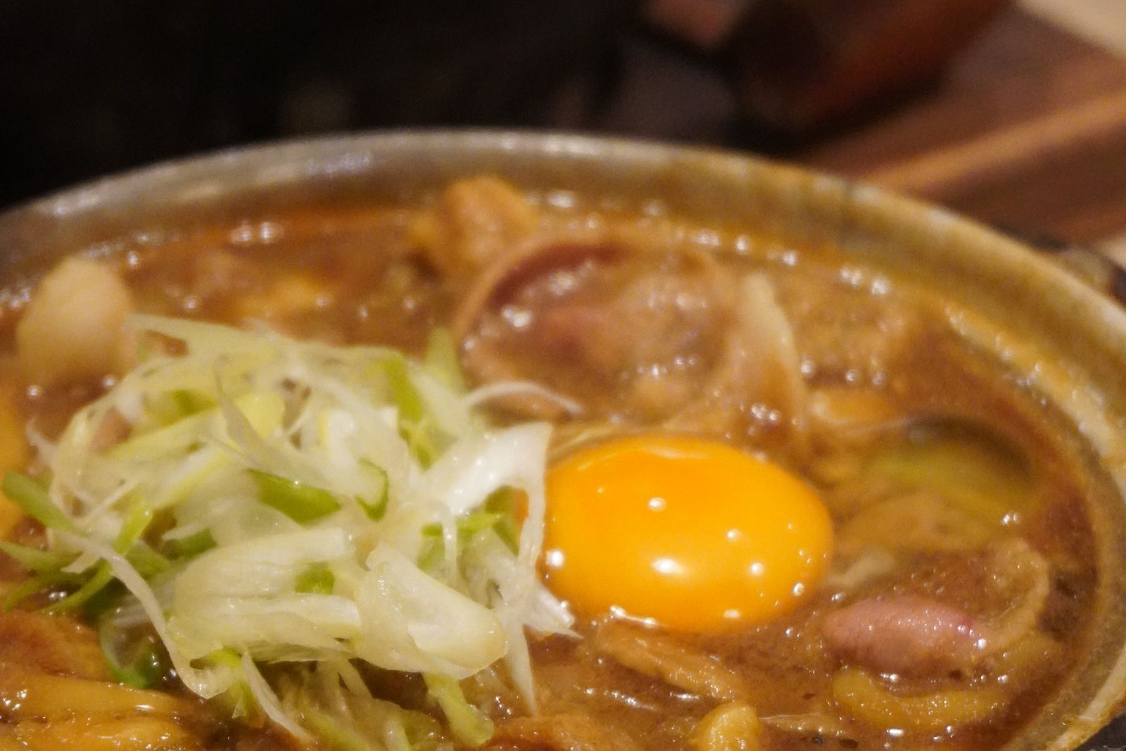 A Japanese hot pot bubbling in an earthenware donabe with a raw egg on top.