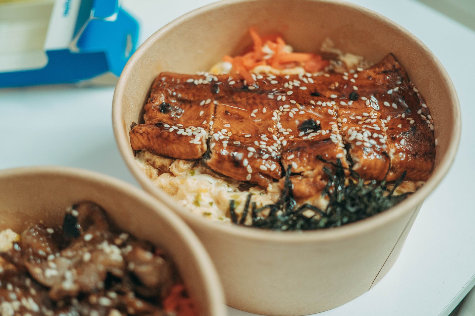 Grilled eel cut into strips over rice in a dark lacquer bowl.