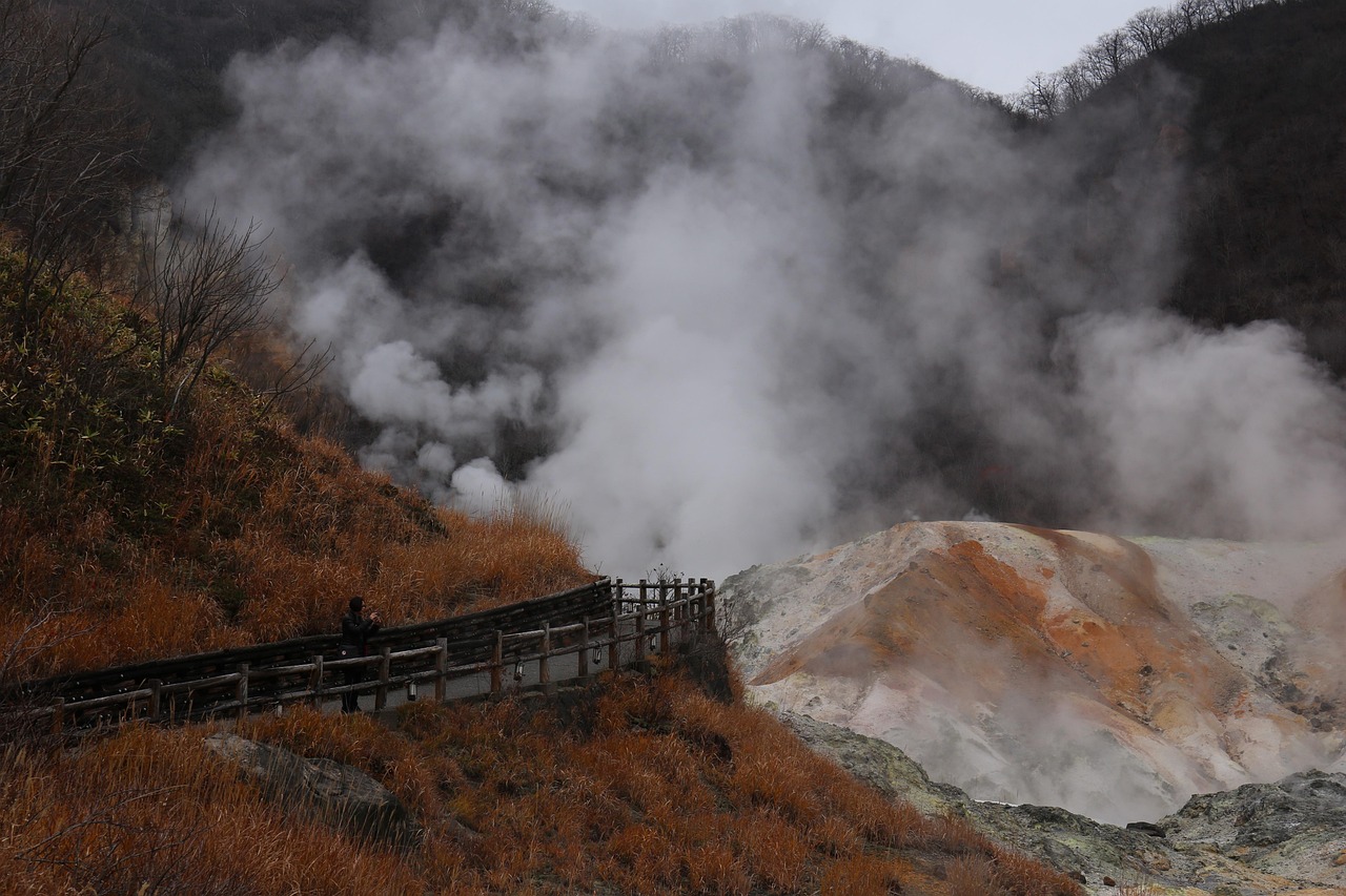 A plume of steam over a volcanic valley seen from a fenced path, Noboribetsu Hell Valley