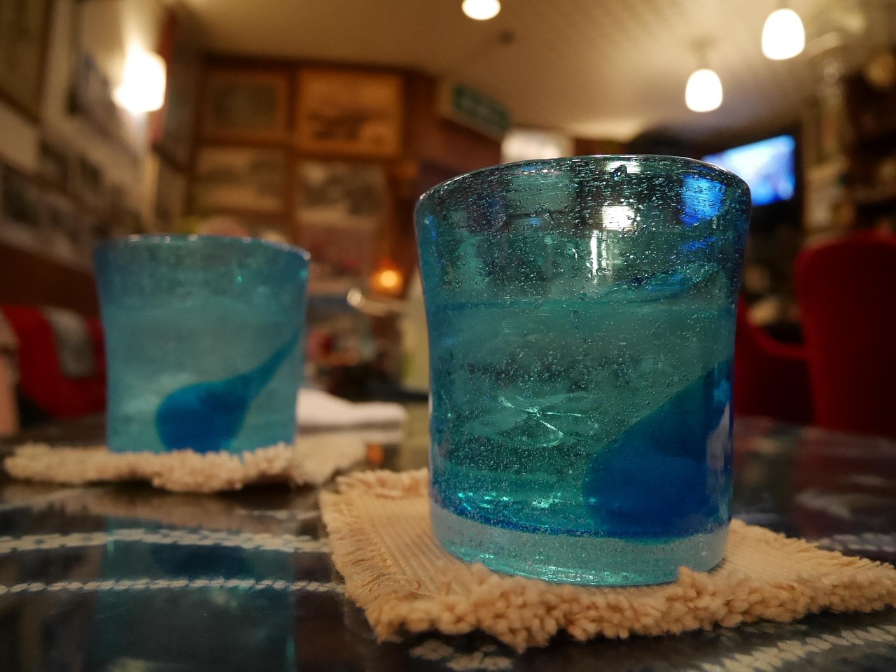 Two blue Ryukyu-style glasses with ice on a bar table