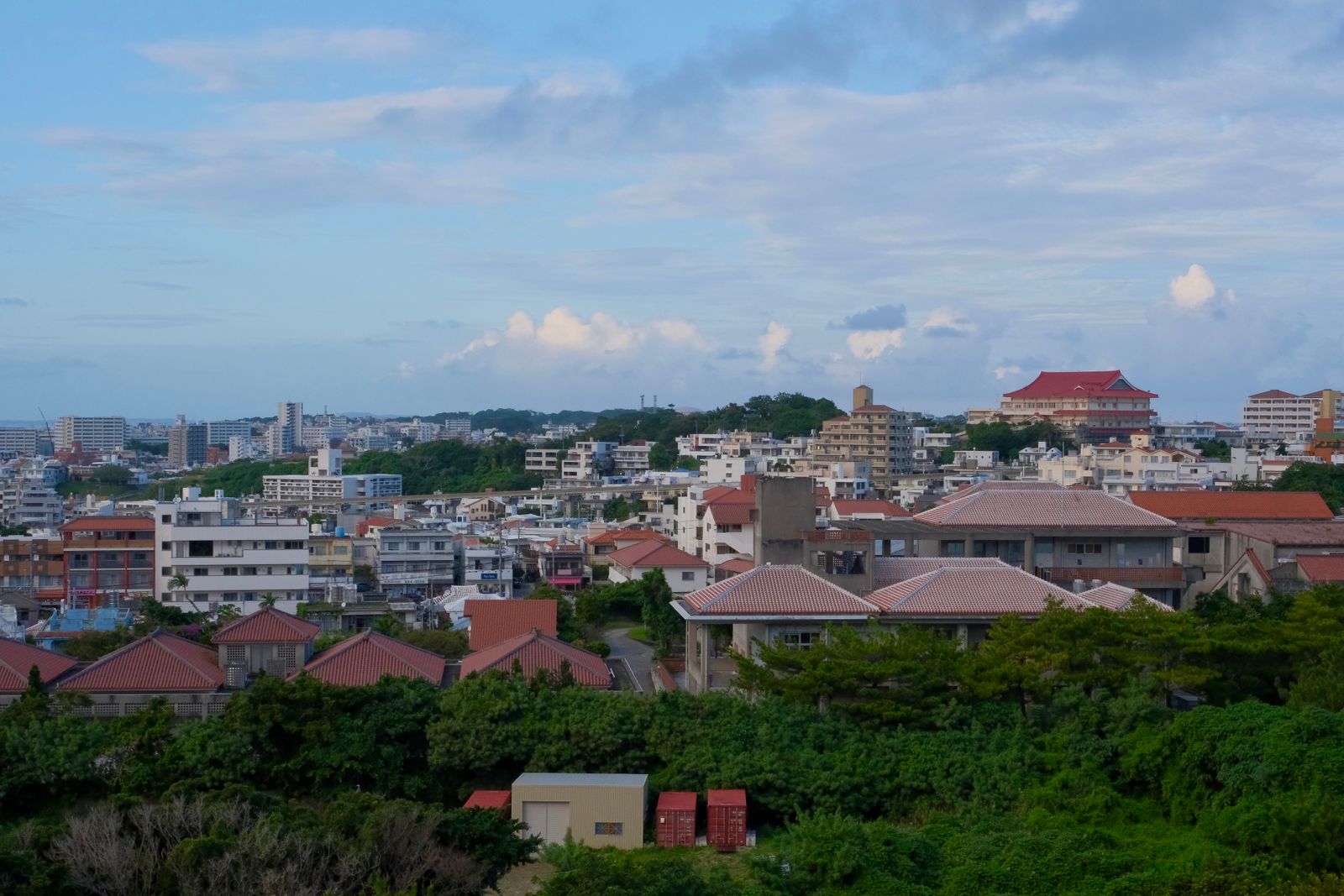 Red-tiled roofs and white apartment blocks on a hillside in Okinawa