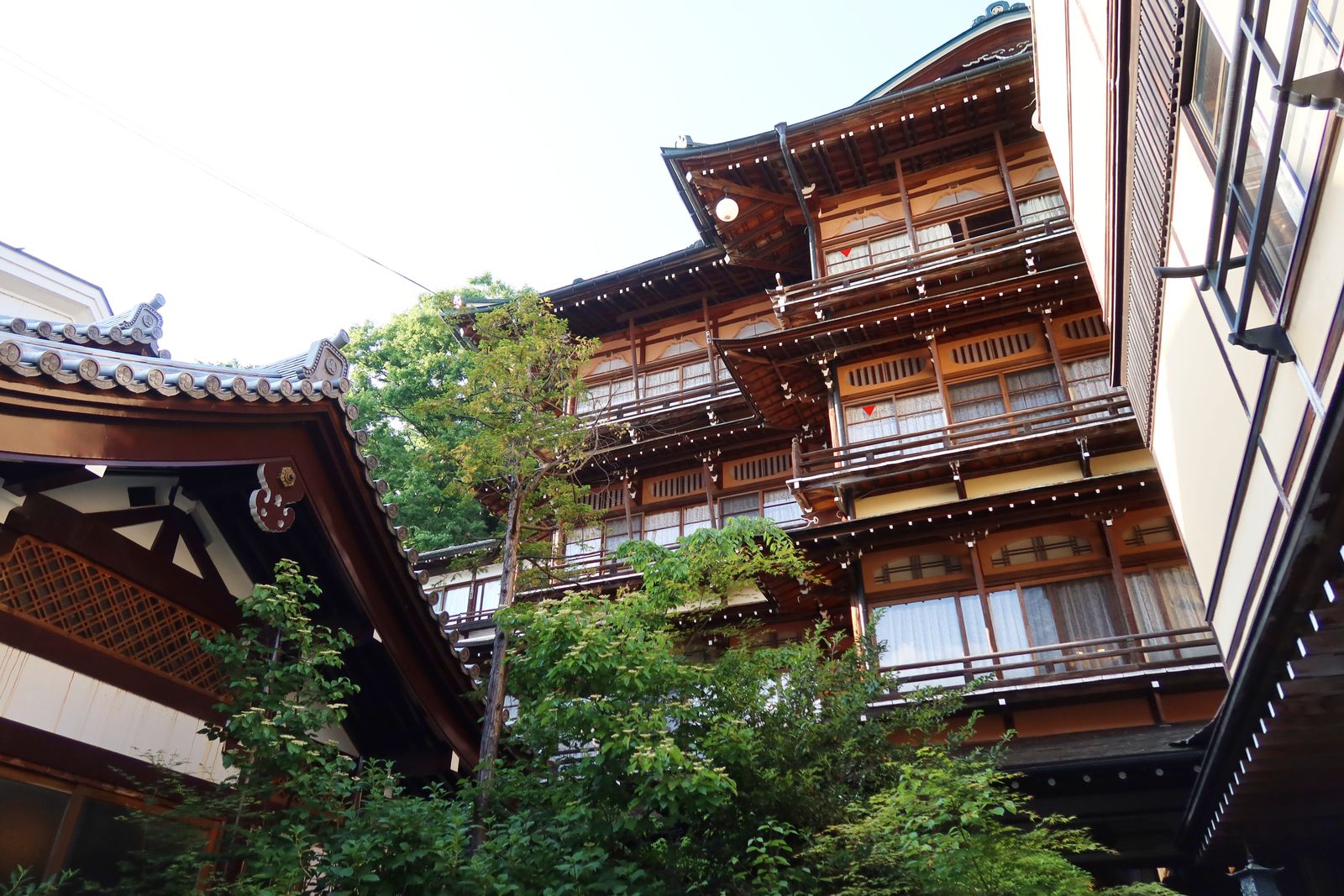 A timber ryokan in Yamanouchi seen from the lane below, with tiled eaves and wooden balconies.