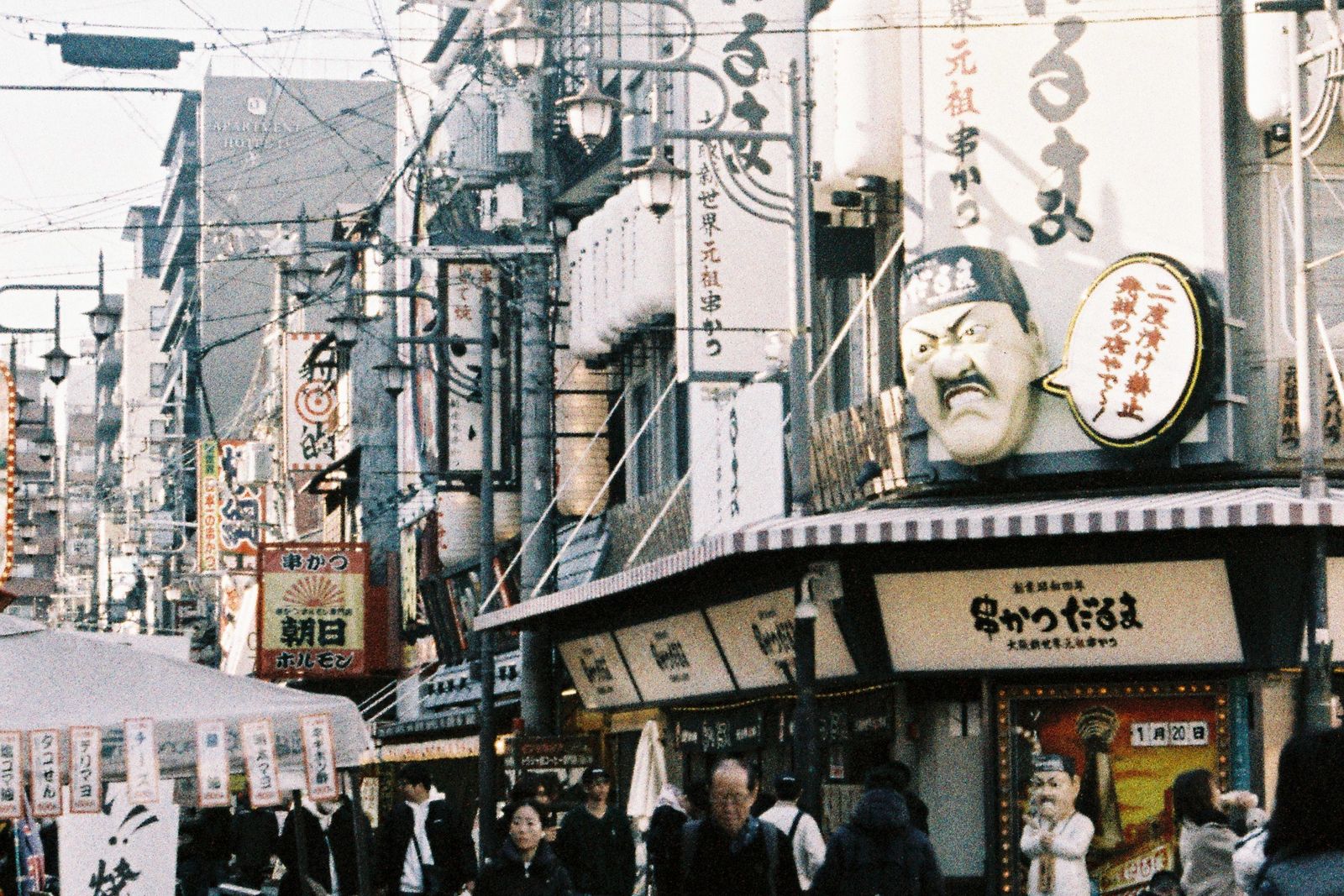 A Shinsekai street lined with kushikatsu shops, vertical signage and a no-double-dipping notice.