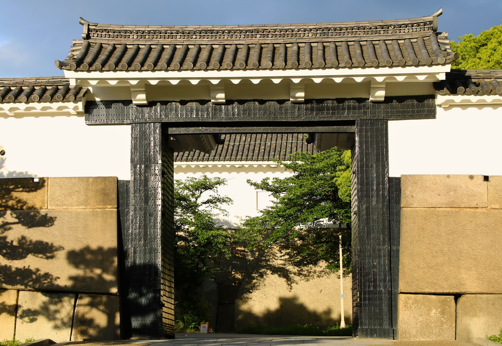 A castle gate with a tiled roof and a dark wooden frame set between huge cut stones.