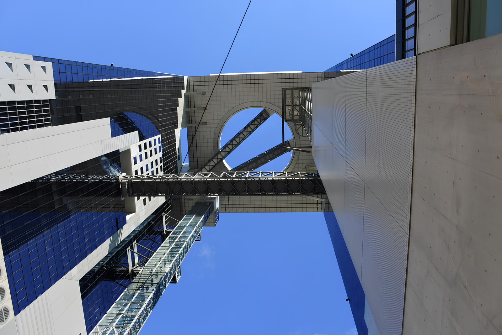 Looking straight up between the two towers of the Umeda Sky Building at the bridges and the open ring at the top.