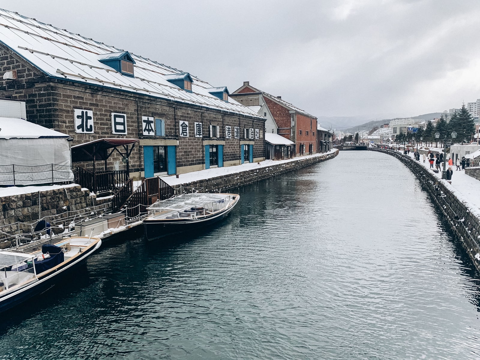 Otaru Canal on an overcast winter day with moored boats and a stone warehouse