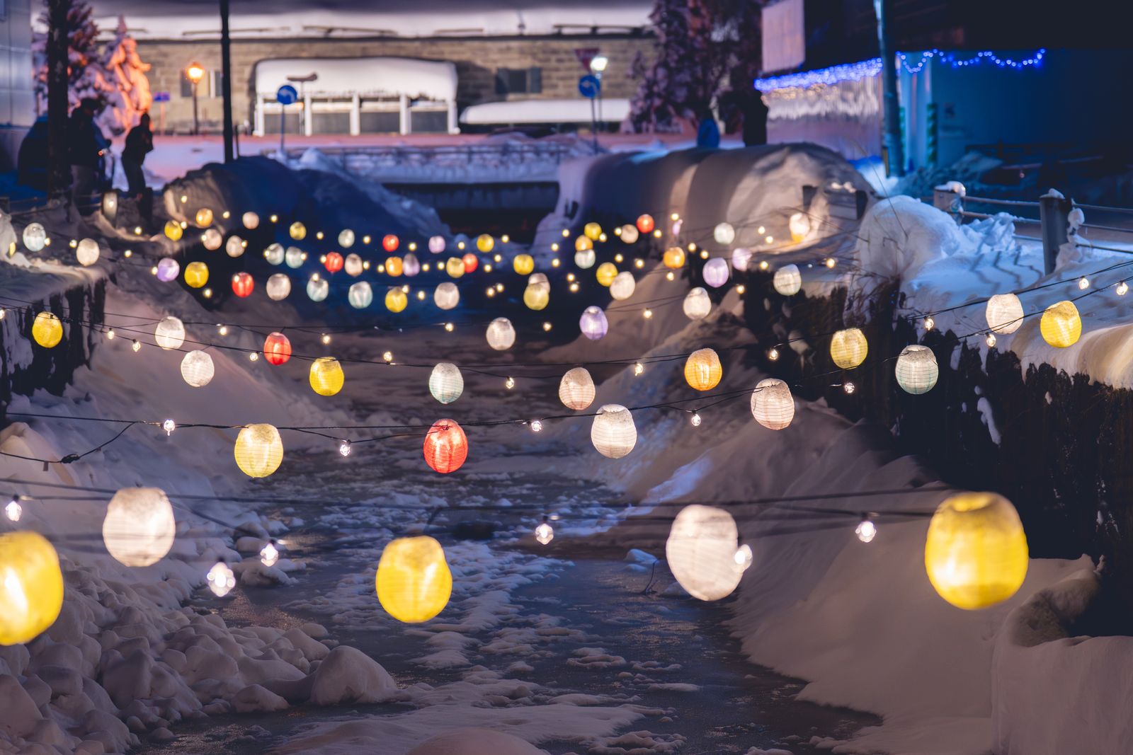 Paper lanterns strung over a snowy channel at night in Otaru