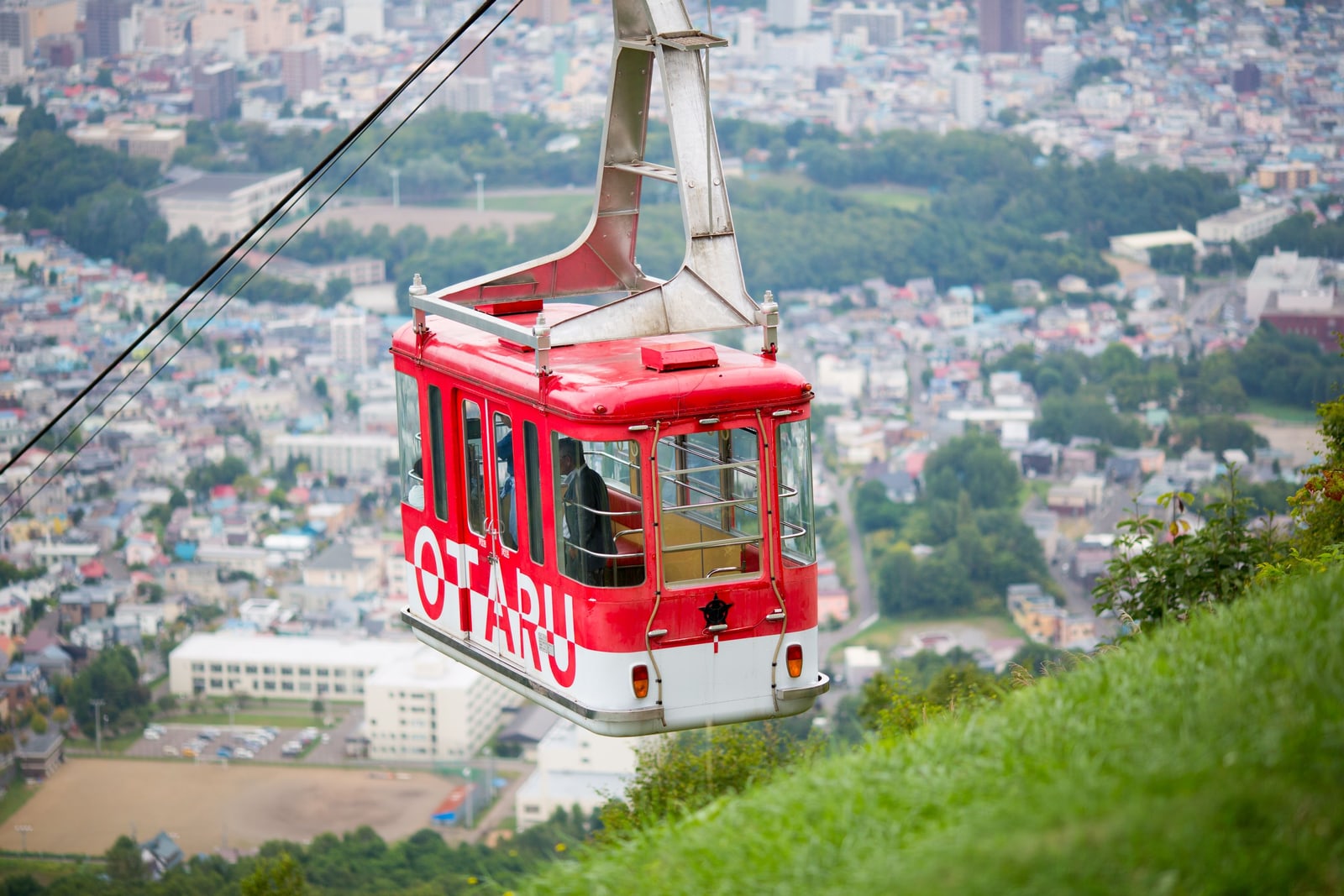 A red ropeway cabin marked OTARU above the town in summer