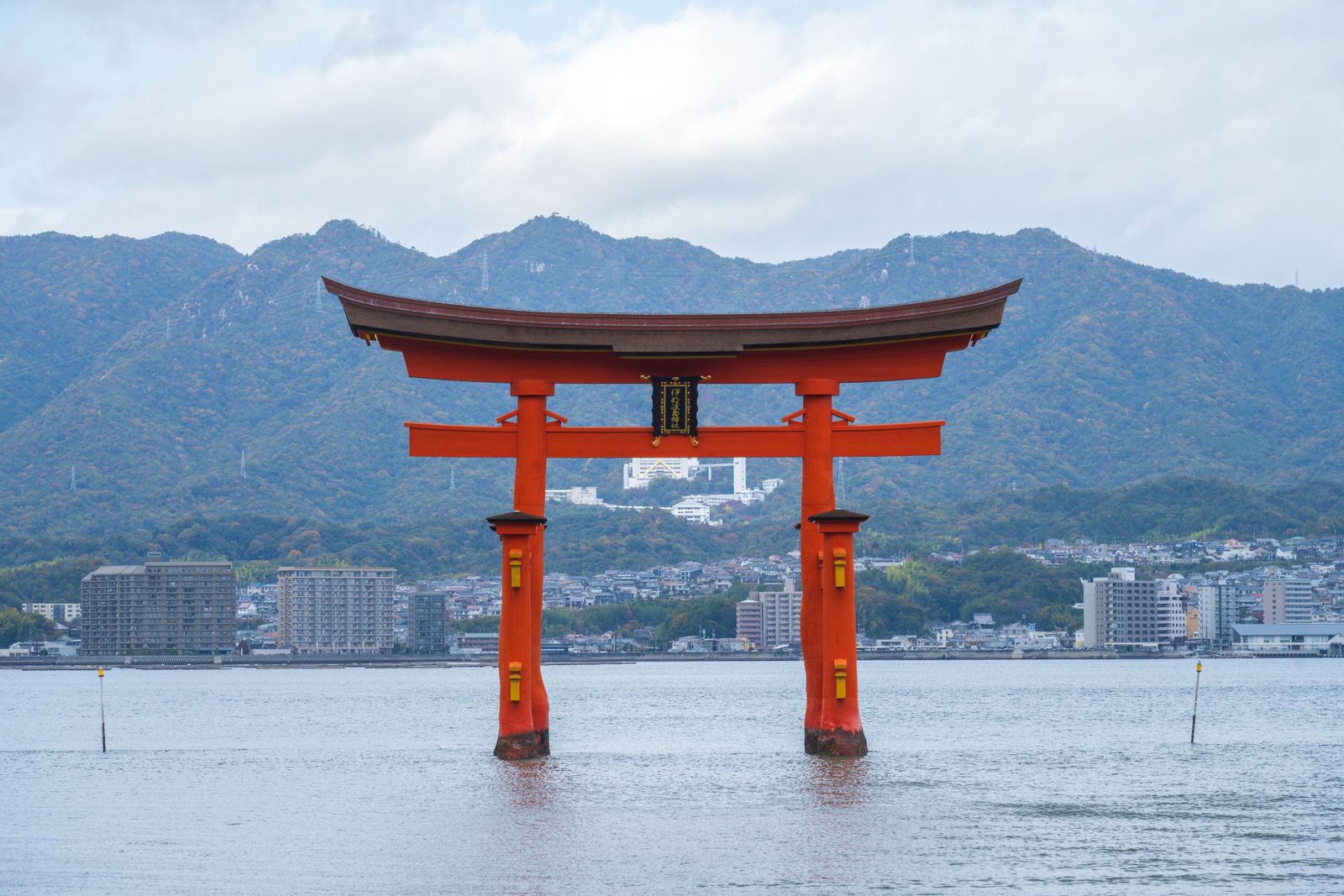 The floating torii of Itsukushima Shrine at Miyajima, seen across the water with the mainland behind it.