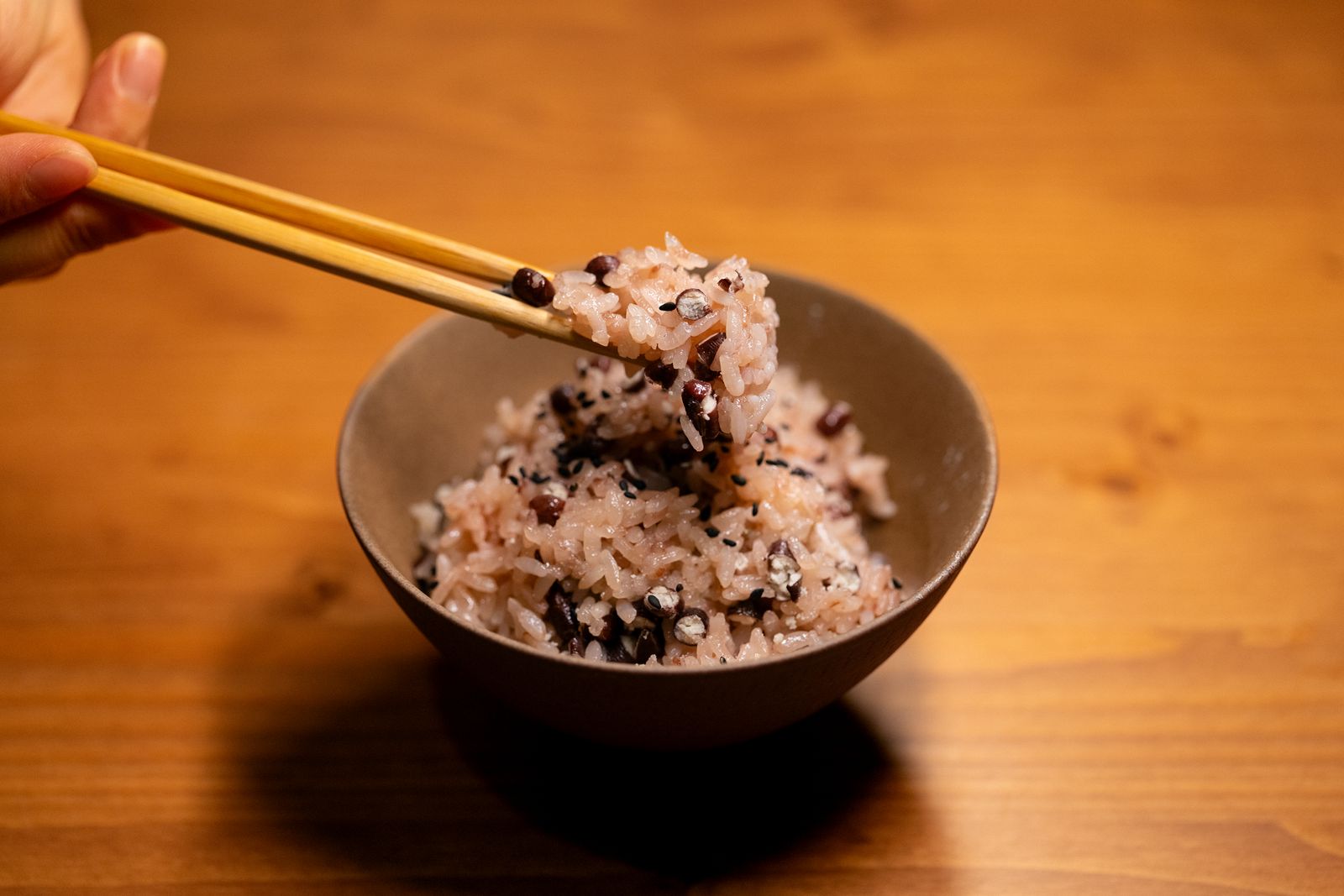 Chopsticks lifting rice from a bowl, the grains separate and glossy.