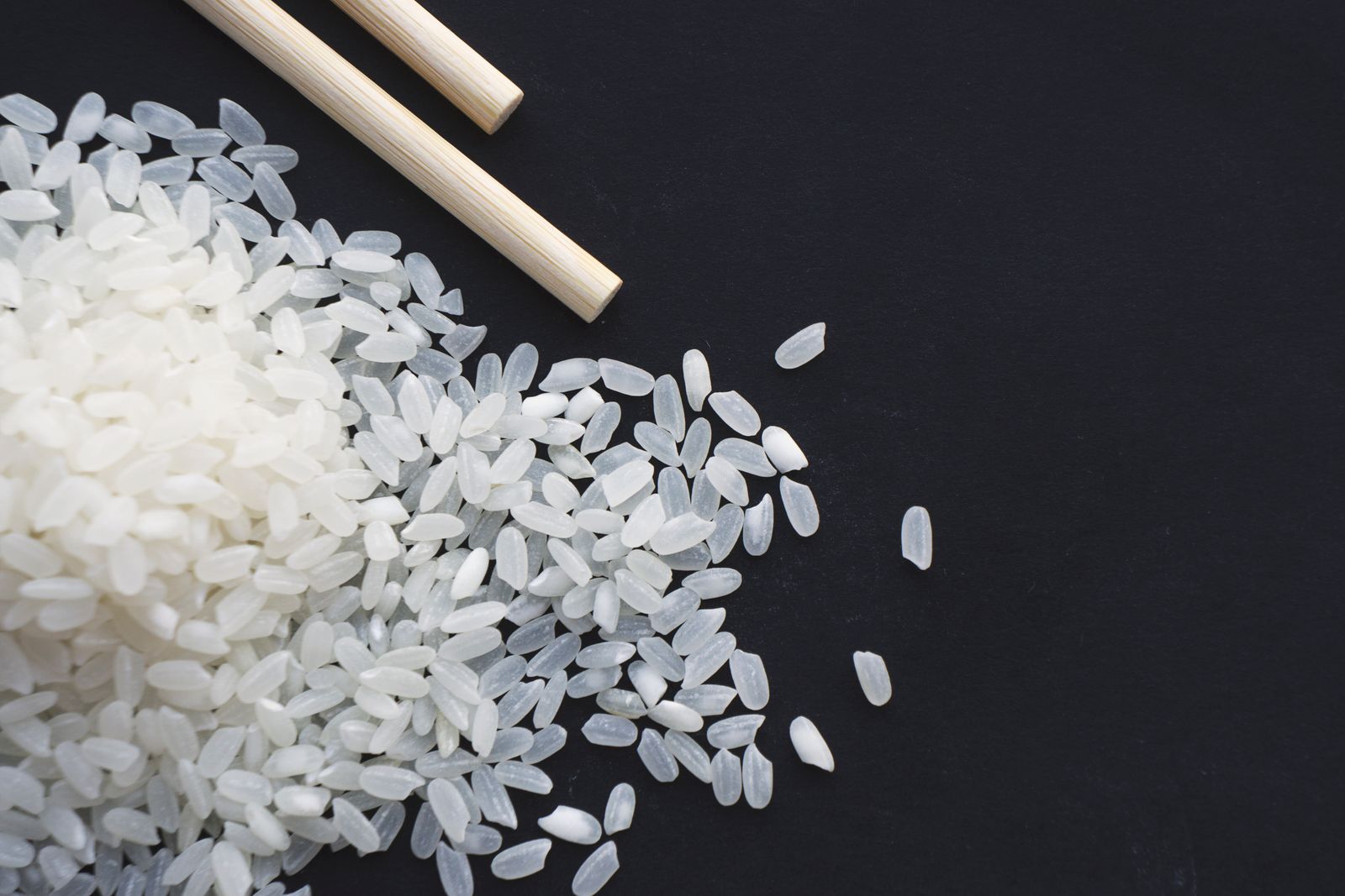 Uncooked rice grains photographed close up against a dark background.