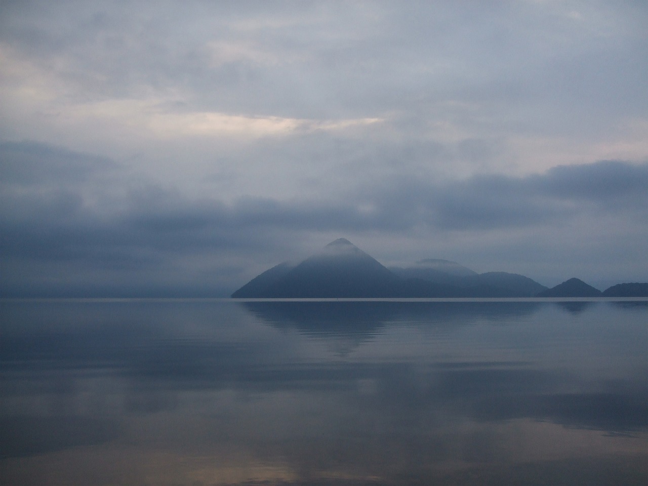 Lake Toya, Hokkaido, with a forested island in mist mirrored in still water