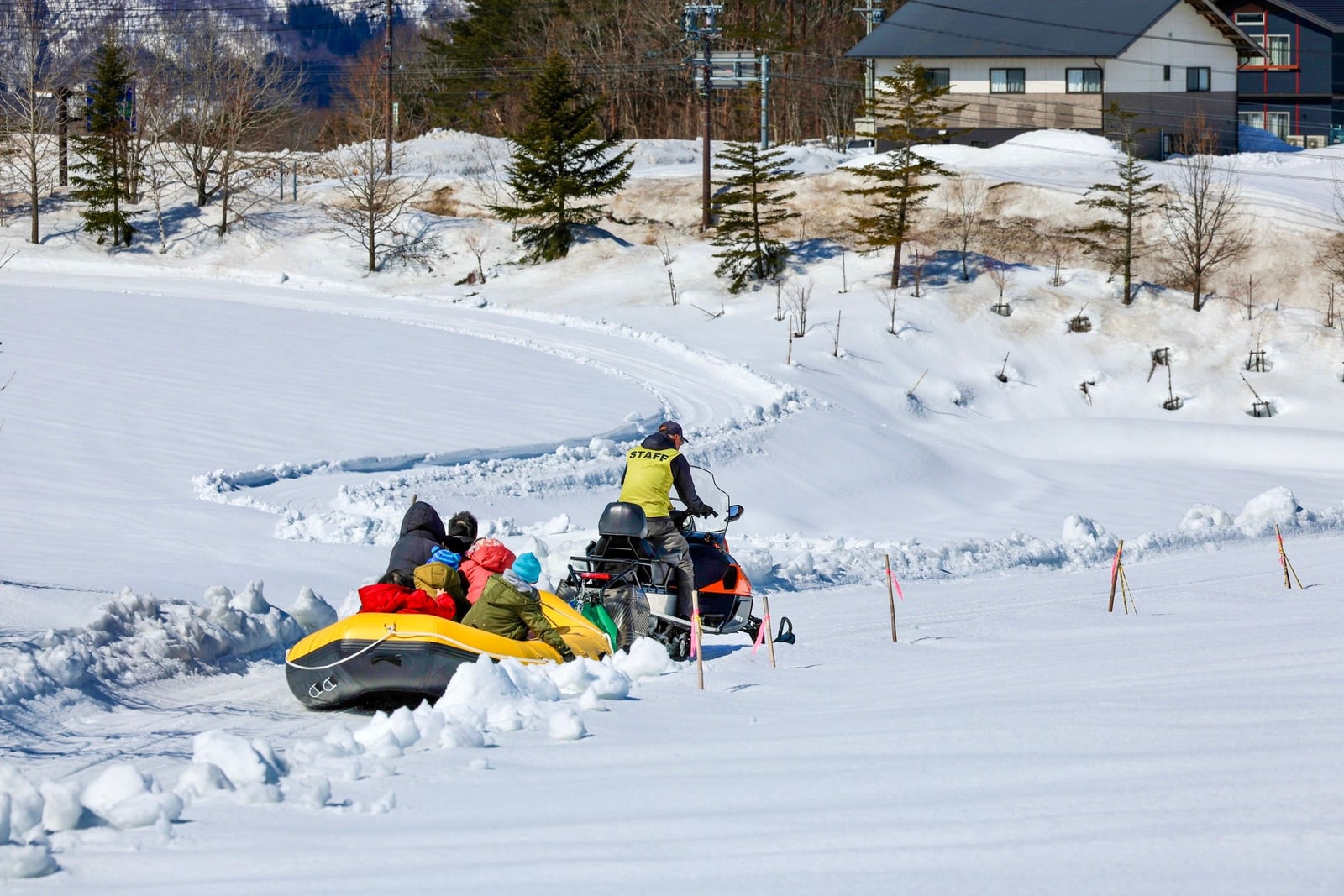Snow rafting in Hokkaido: a yellow raft of passengers towed across deep snow by a snowmobile