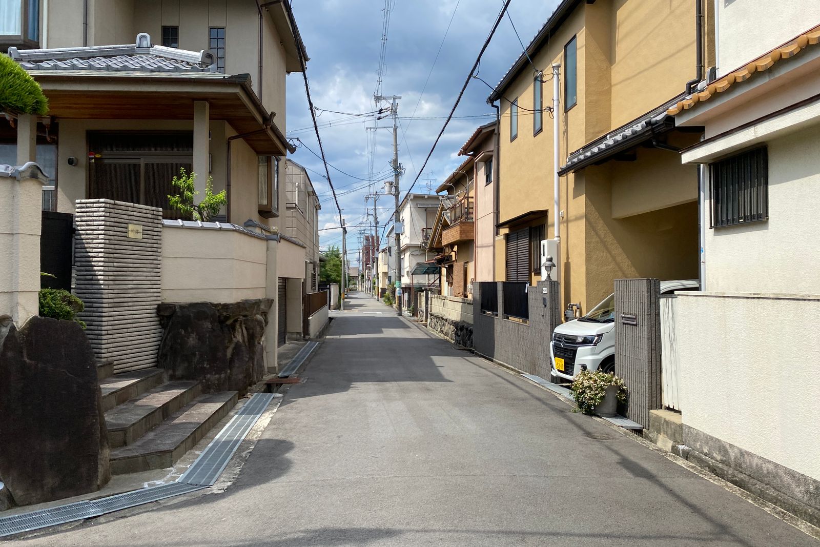 A quiet Japanese residential street in bright daylight, no people in the frame.