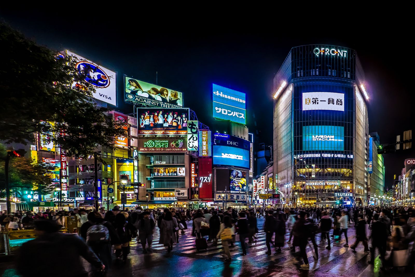 Shibuya scramble crossing at night, the crowd blurred and seen from behind.