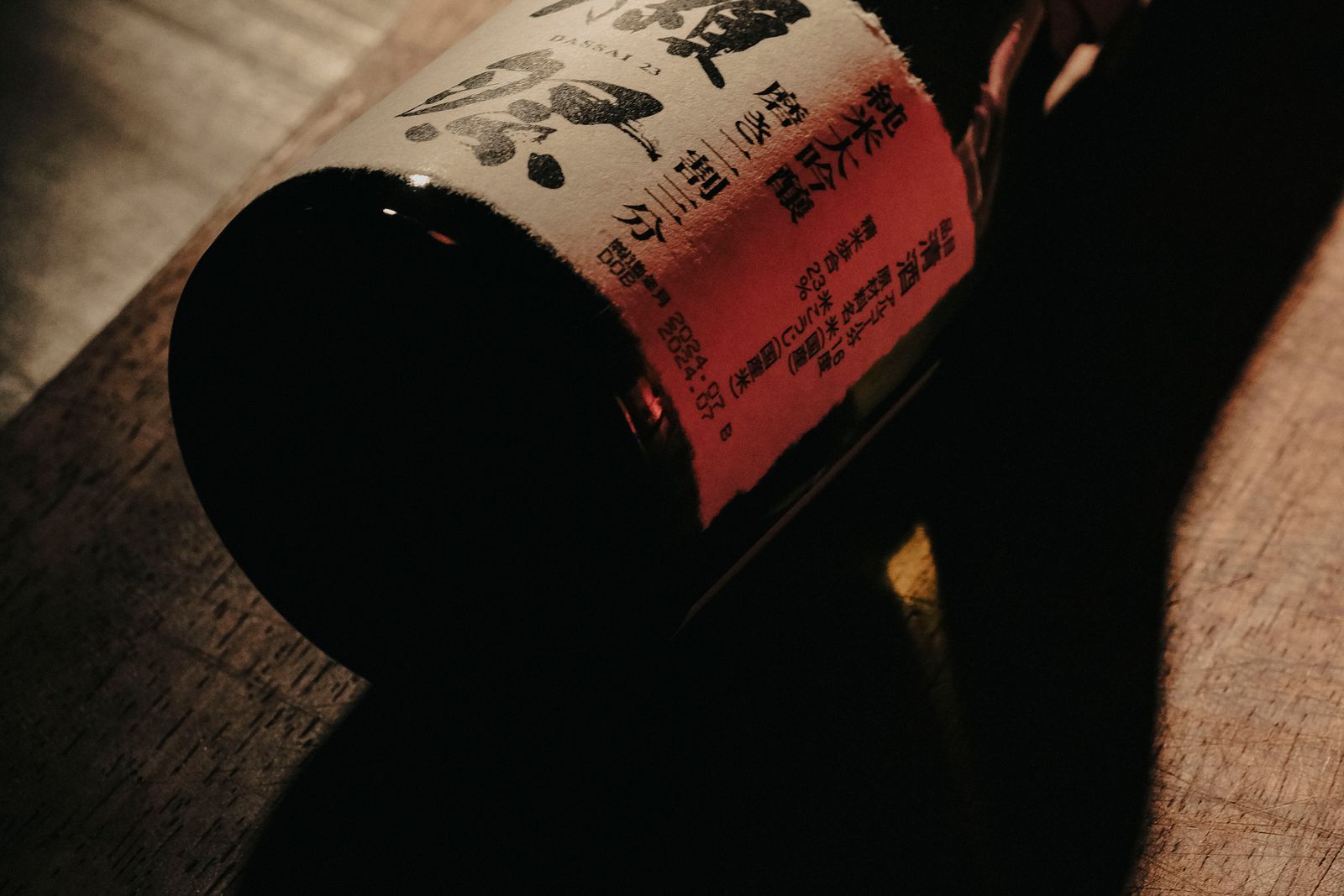 A sake bottle lying on wood, the printed detail on its label in focus.