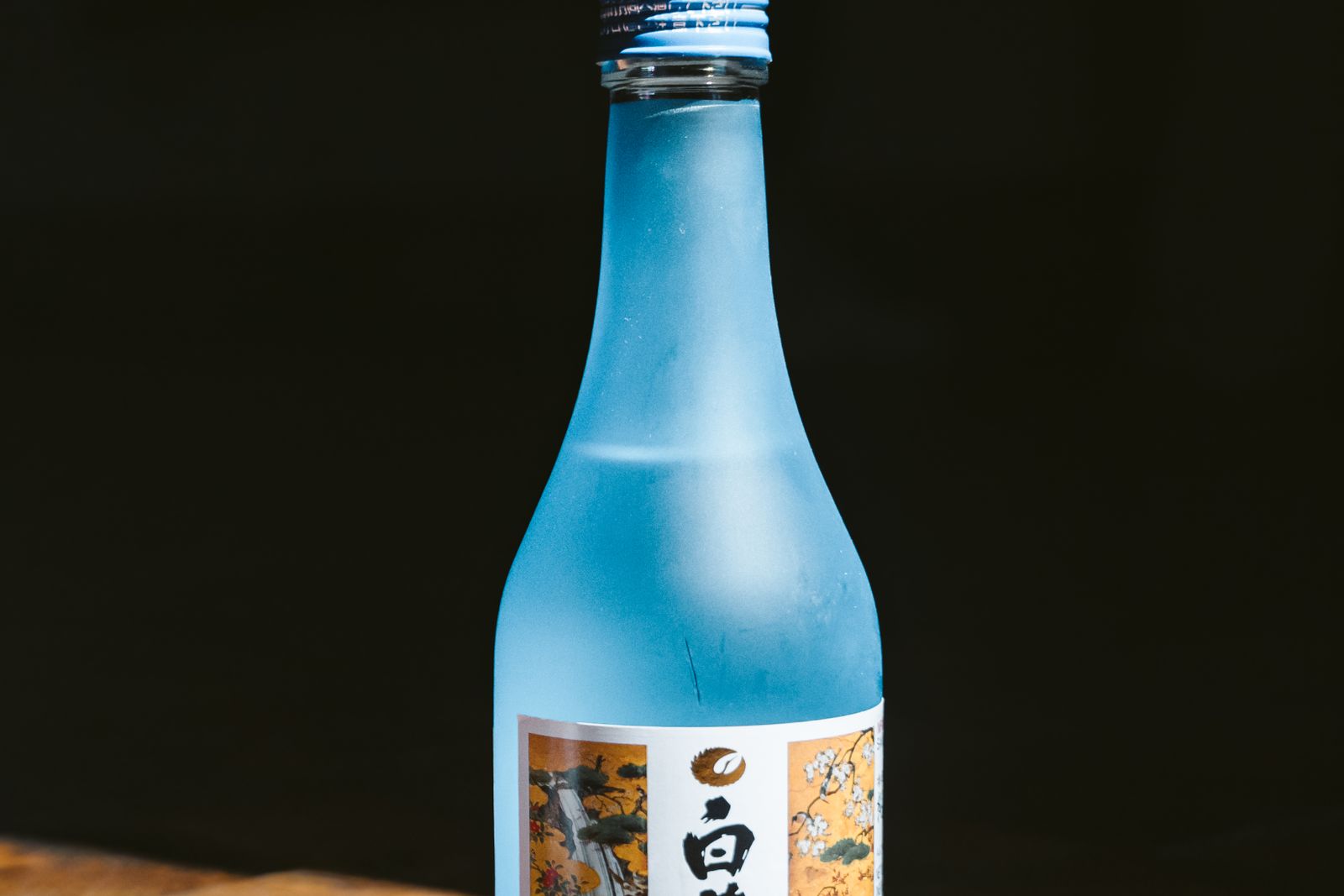 A single pale sake bottle on wood against a black background, its label cropped by the frame.